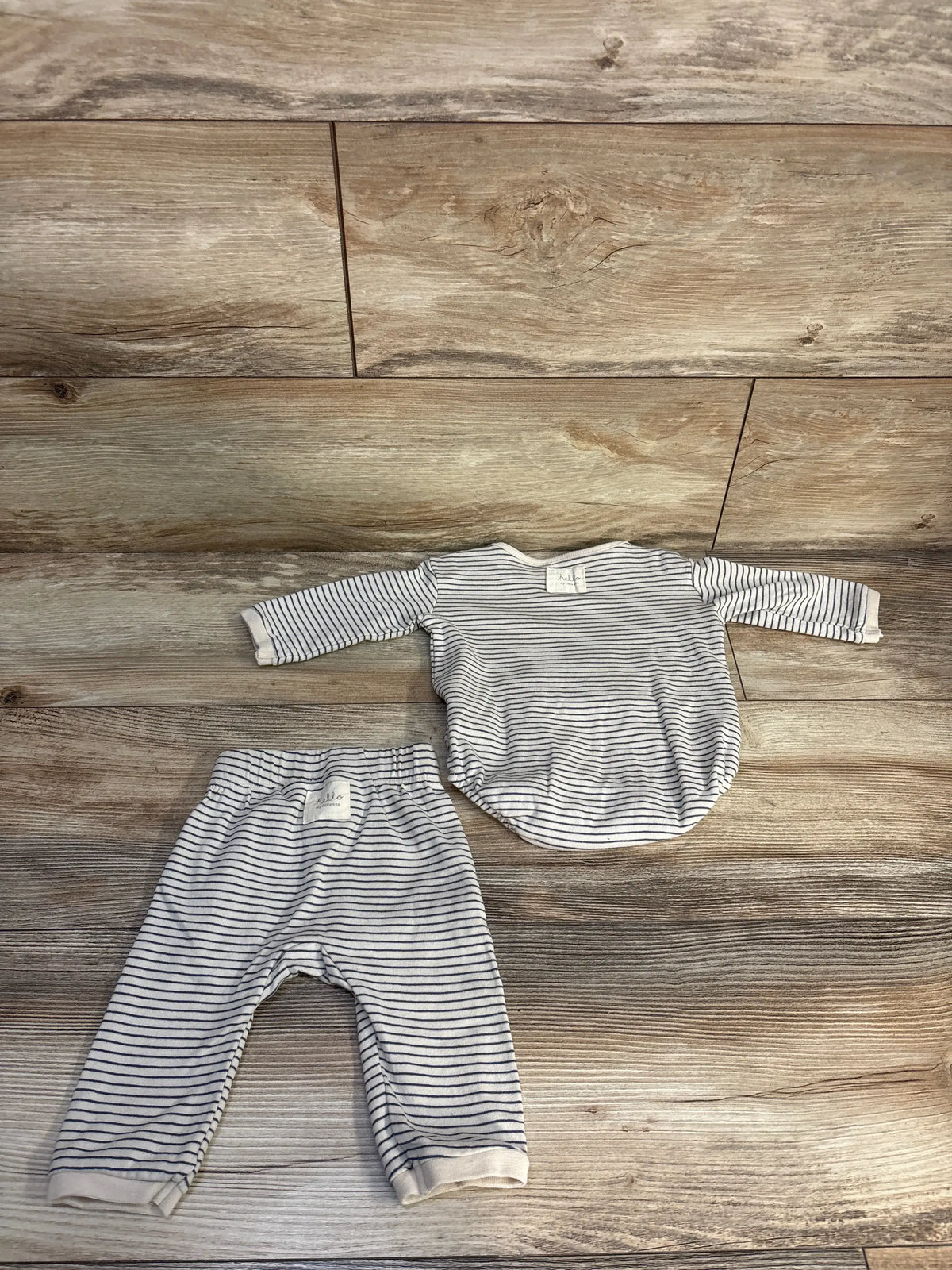 Top-down view of H&M organic cotton two-piece baby set with cream stripes, long sleeves, matching pants, and wood floor