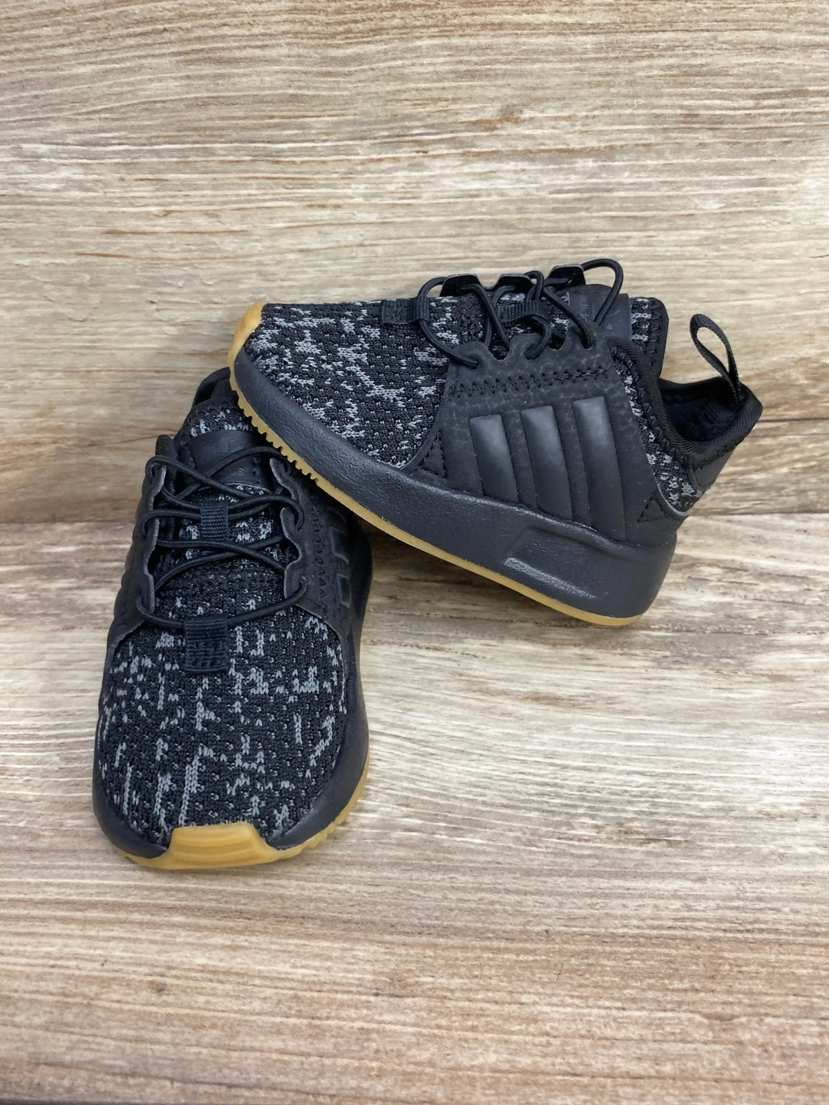 Black and gray kids athletic sneakers with gum soles on wood background
