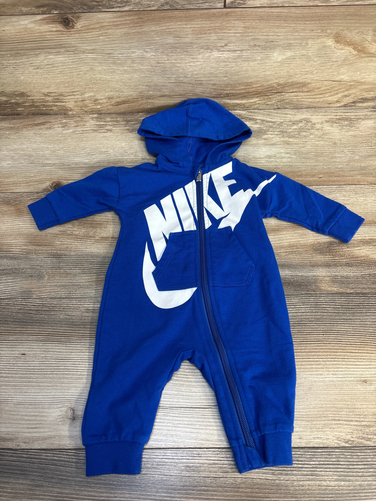 Blue hooded baby romper with front zipper and white graphic on wooden background