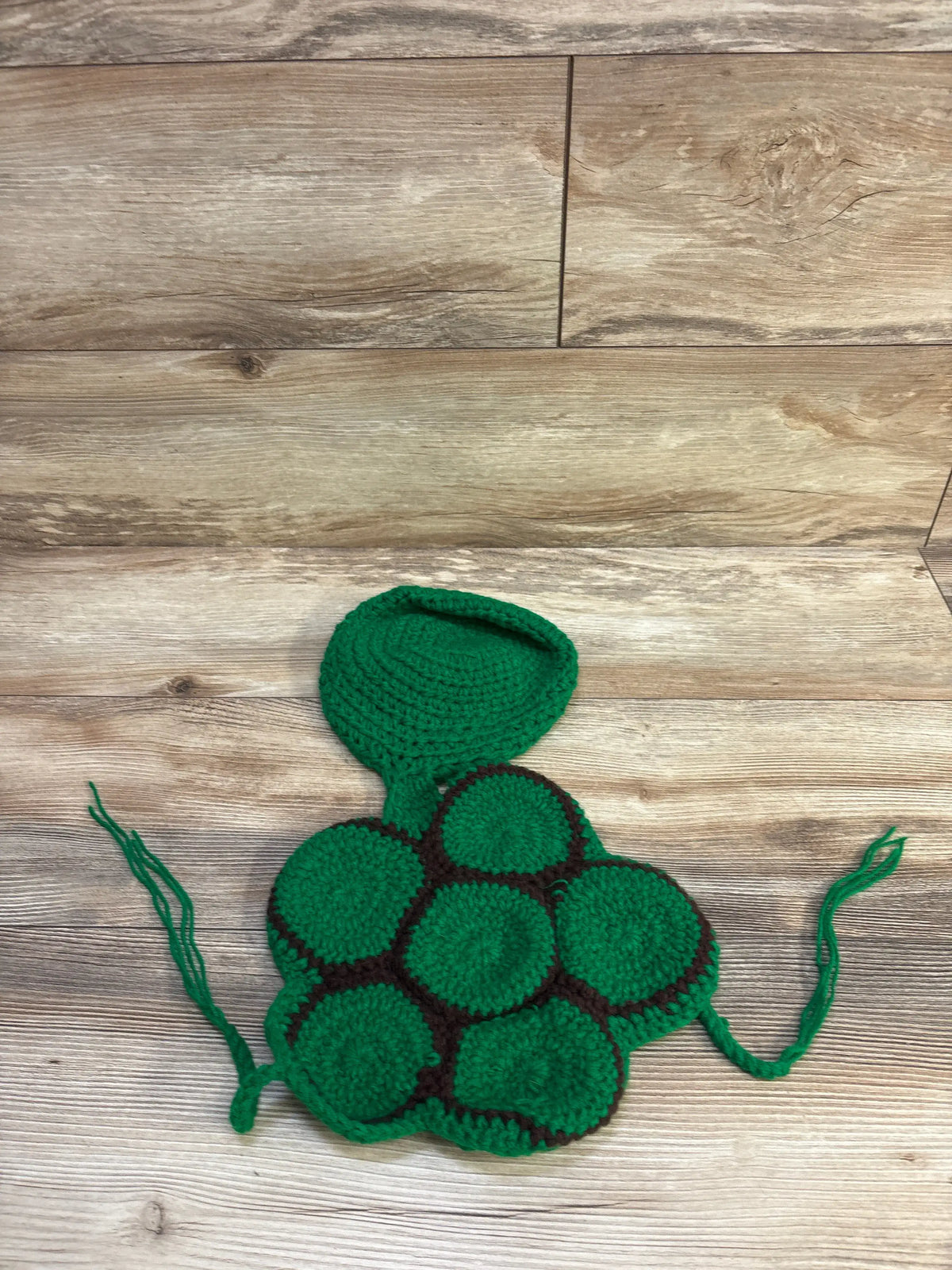 Green crochet newborn turtle photo prop costume by Me n Mommy To Be on a wooden background