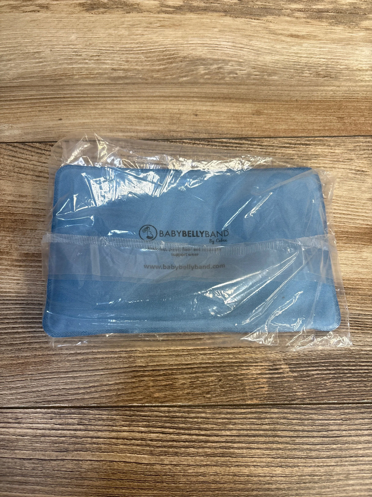 Blue BabyBellyBand maternity support band in packaging on wood surface
