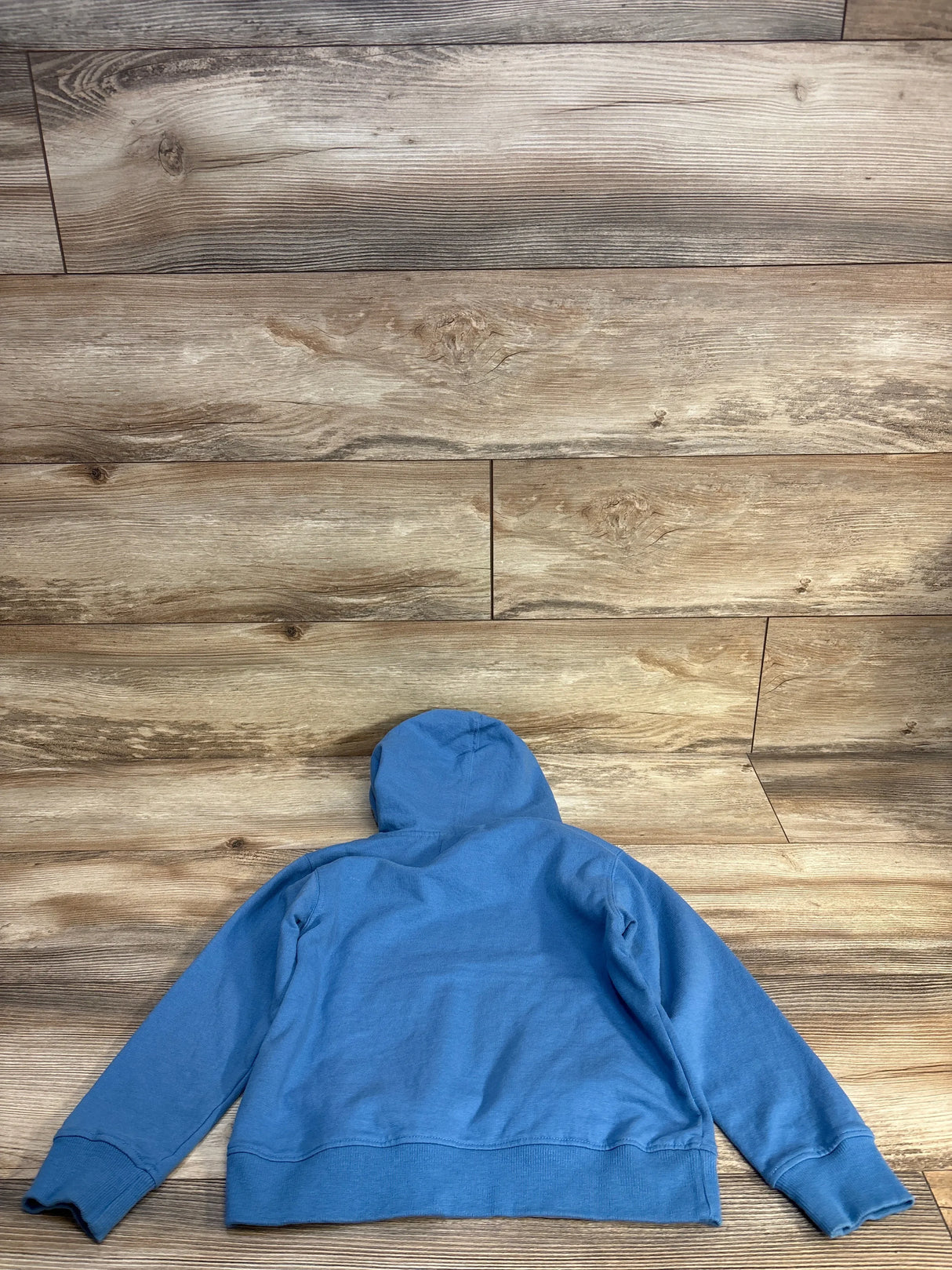 Blue kids hoodie sweatshirt laid flat on wood floor background