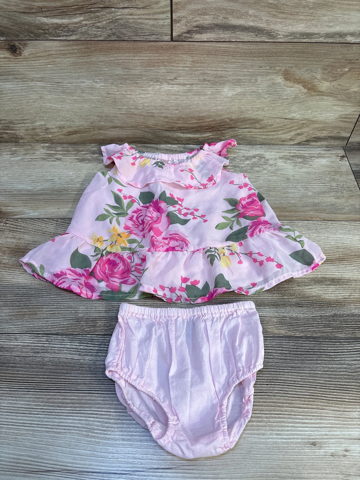 Pink floral baby dress with matching bloomers on wooden background