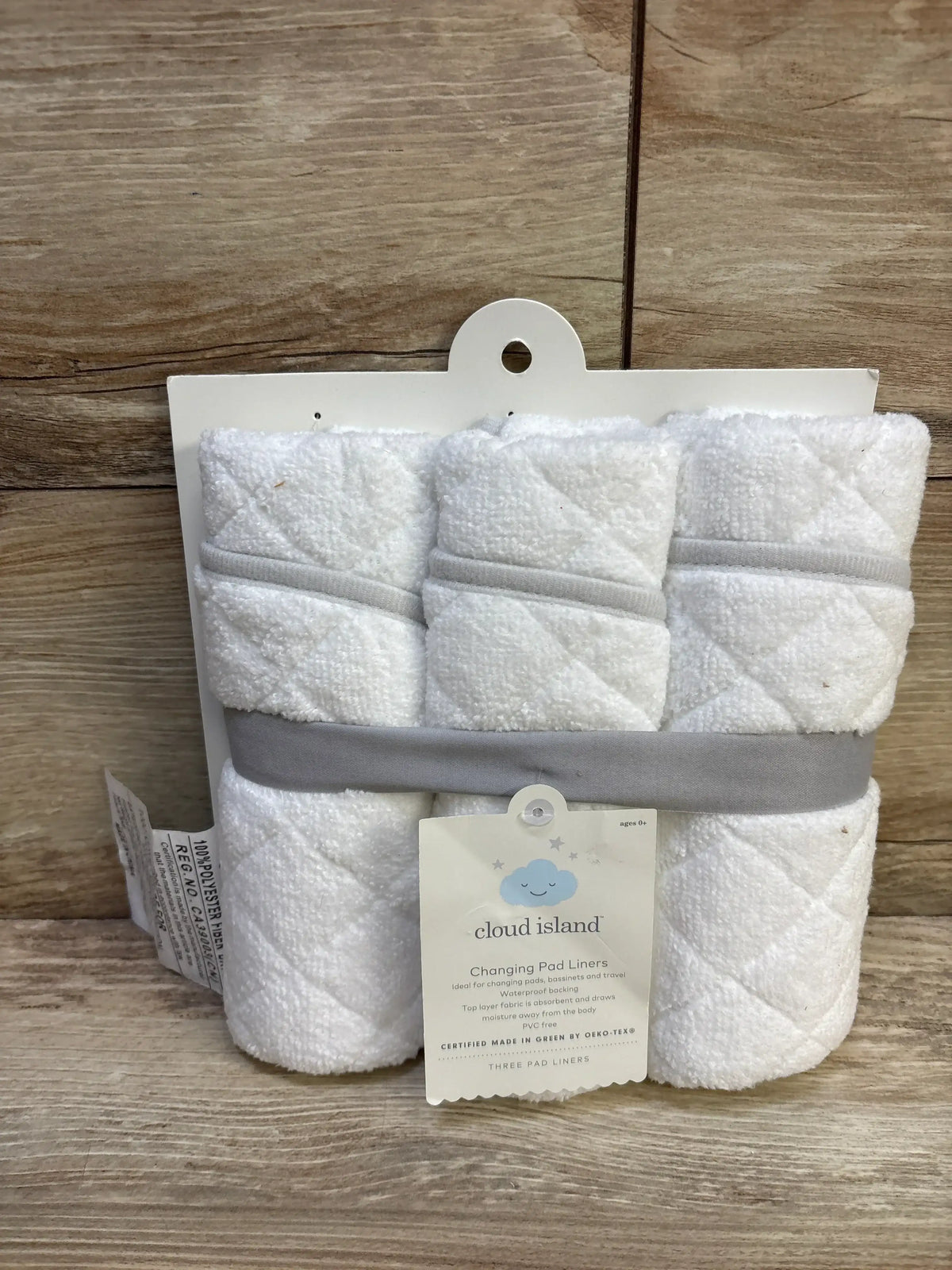 Front view of Cloud Island changing pad liners 3-pack showcasing quilted white terry absorbent surface and gray band on wood background