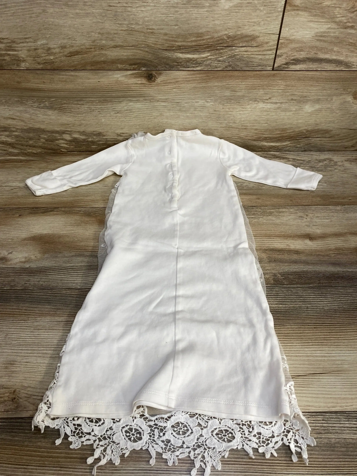 Back view of Biscotti lace christening gown, white 3-6m, showing button-back, long sleeves and lace hem on wood background