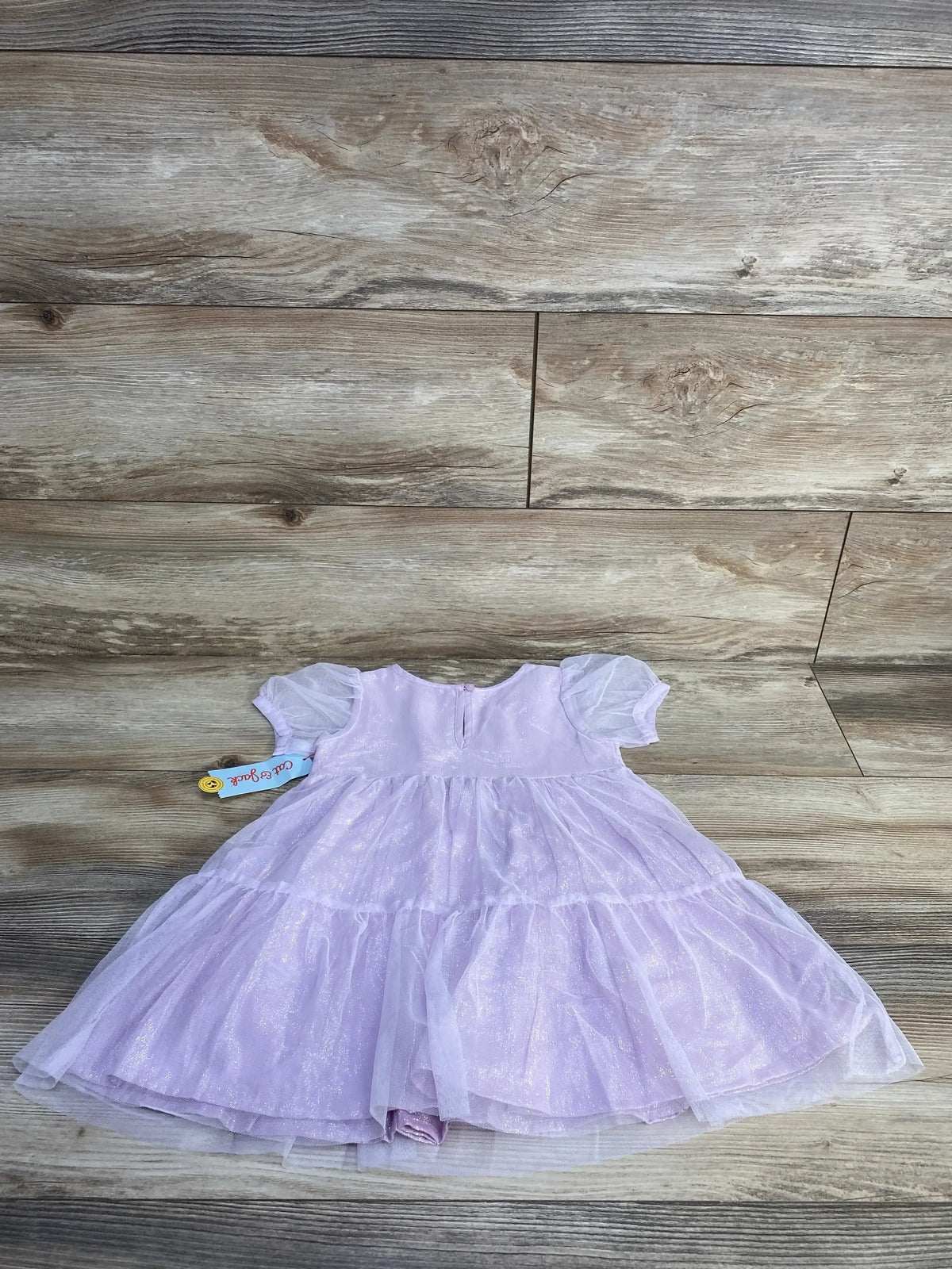 Flat lay of Cat and Jack 2T purple toddler dress showcasing layered glitter tulle overlay, puff sleeves and tiered skirt on light wood floor
