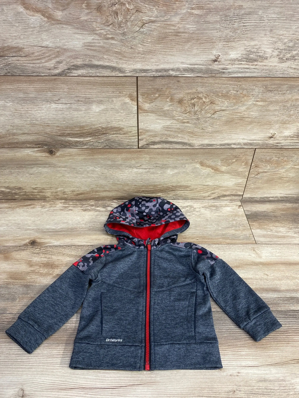 Kids' dark gray hooded jacket with red zipper and camo print shoulders on wooden floor