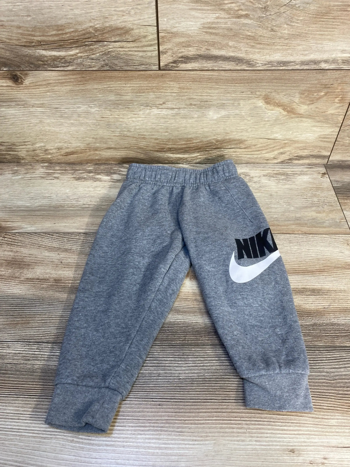 Gray Nike toddler sweatpants with logo on wooden floor