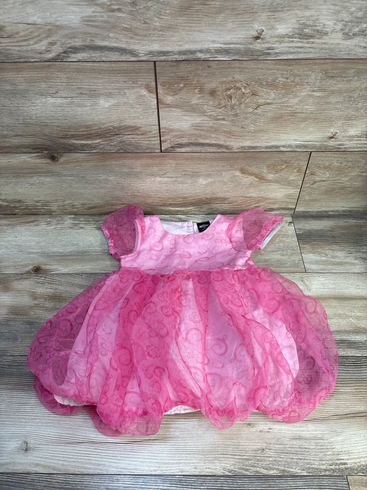 Front view of Wicked Glinda dress in pink, size 3T, showcasing square neck and short puffed sleeves on wood floor