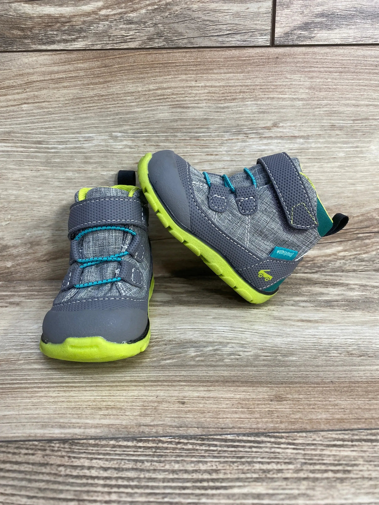 Front and side view of See Kai Run Sam II toddler waterproof grey boots with lime green soles and teal accents on wood background