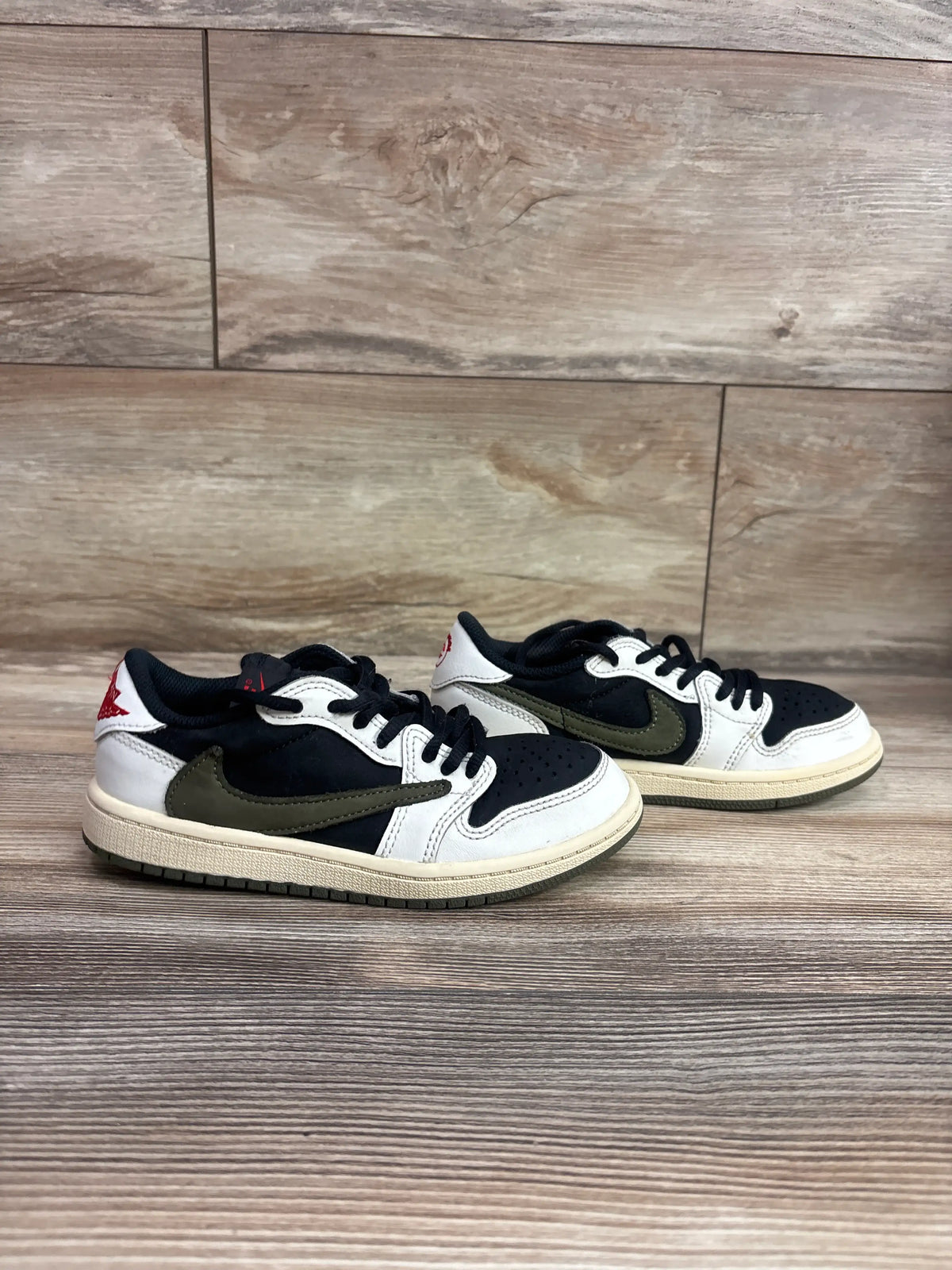 Angled view of Travis Scott Air Jordan 1 Retro Low Olive sneakers with black white and olive panels on wood flooring