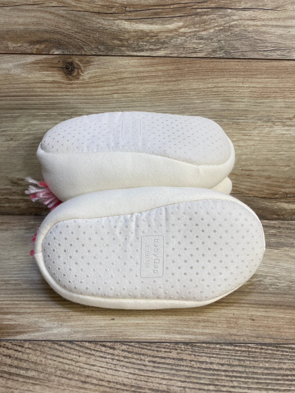 White Baby Gap infant shoes with textured soles on wood background, gently used baby footwear