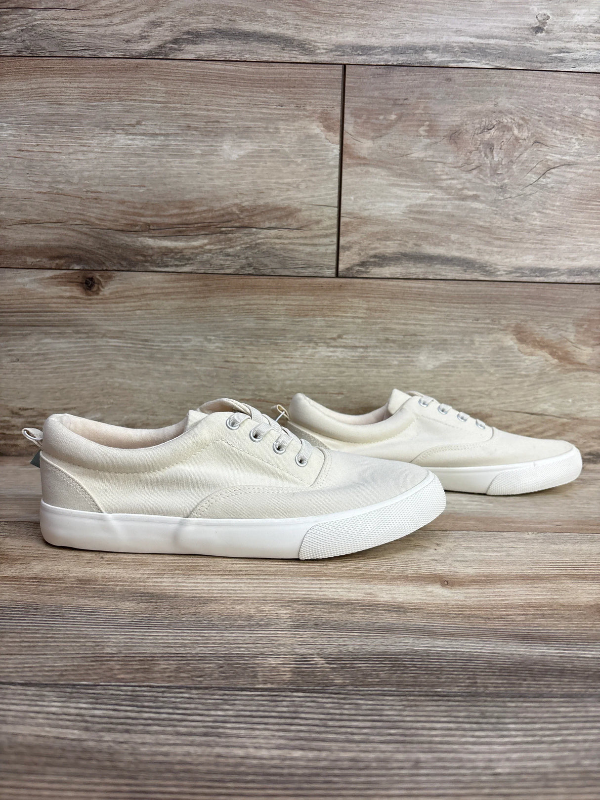 Kids cream canvas sneakers with white rubber soles on wood background