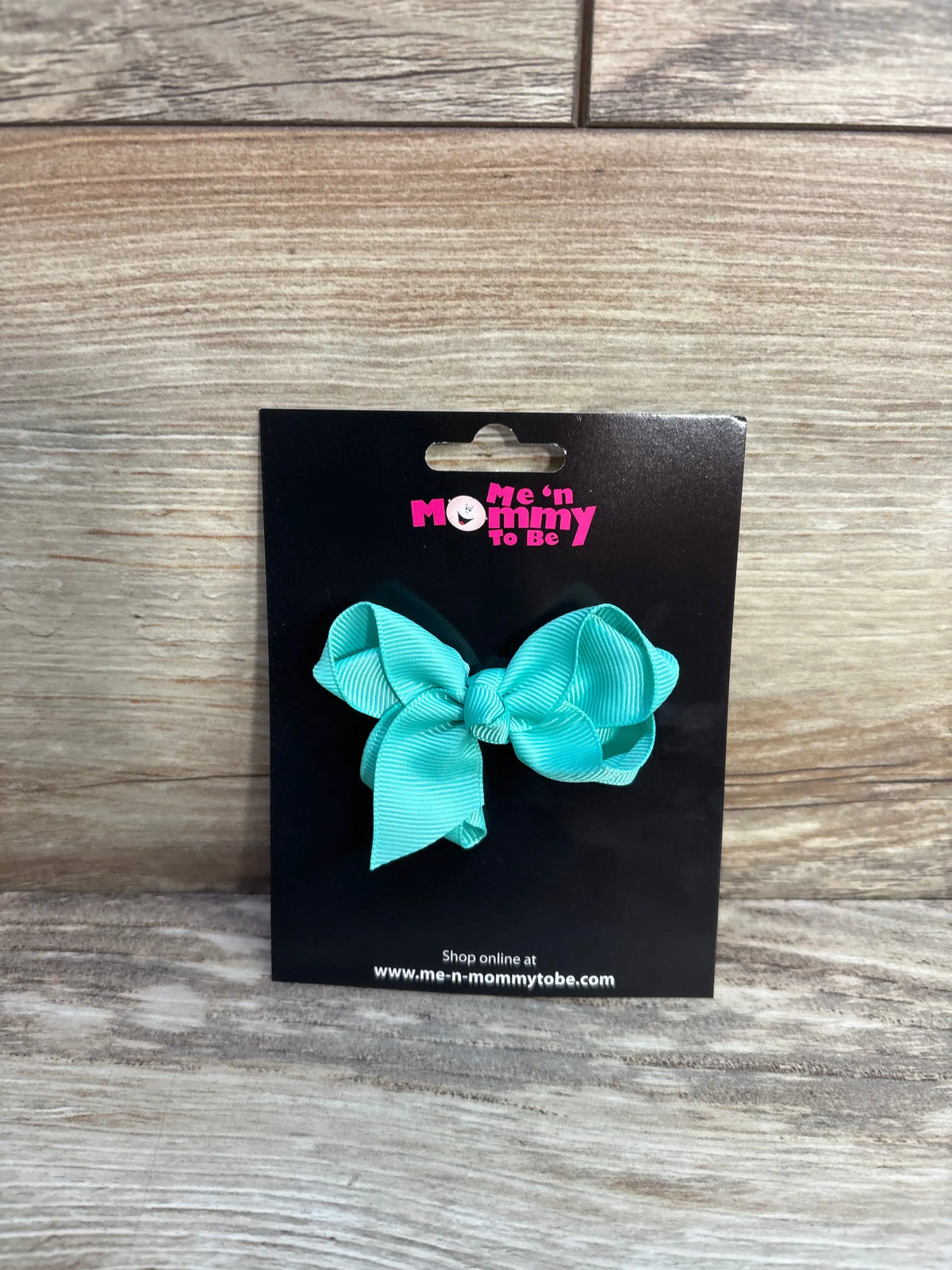 A light blue solid hair bow by Me n Mommy To Be on a black display card.