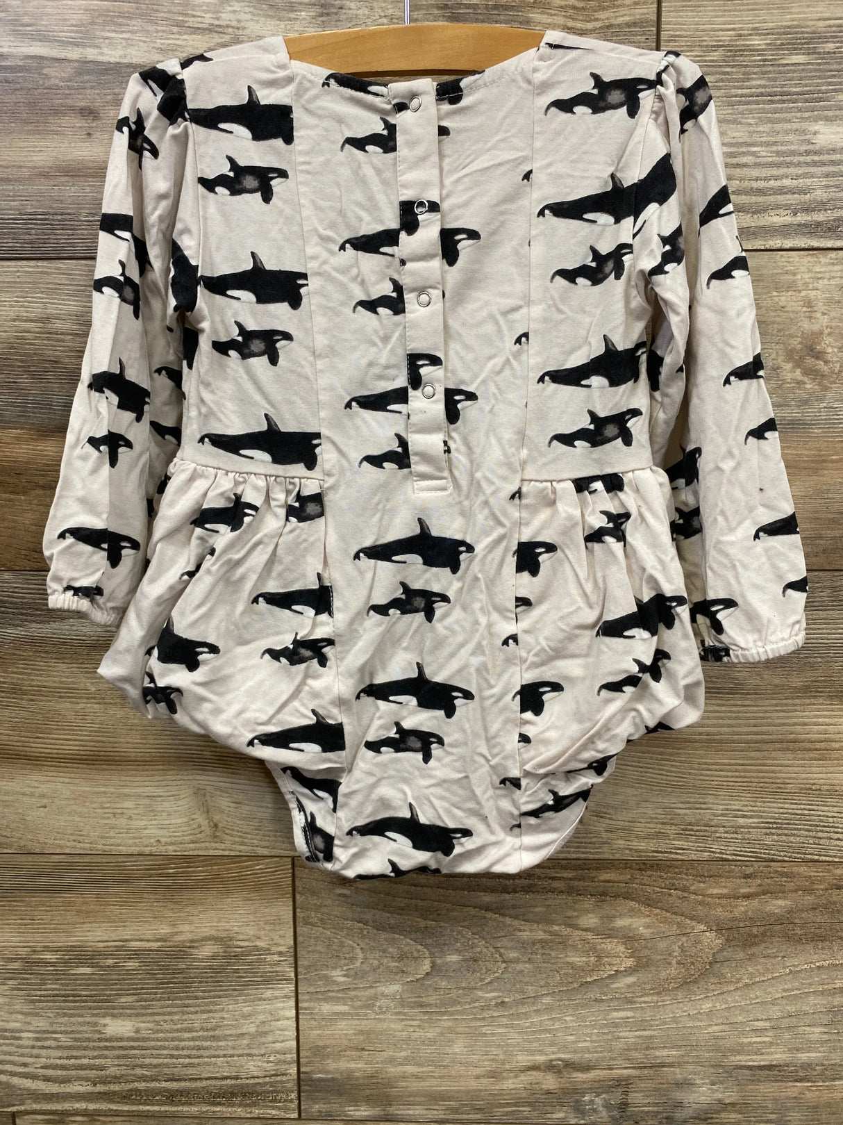 Front view of Kate Quinn Orca Whale Skirted Bodysuit showcasing long sleeves, orca print, and gathered tulle skirt overlay on wood