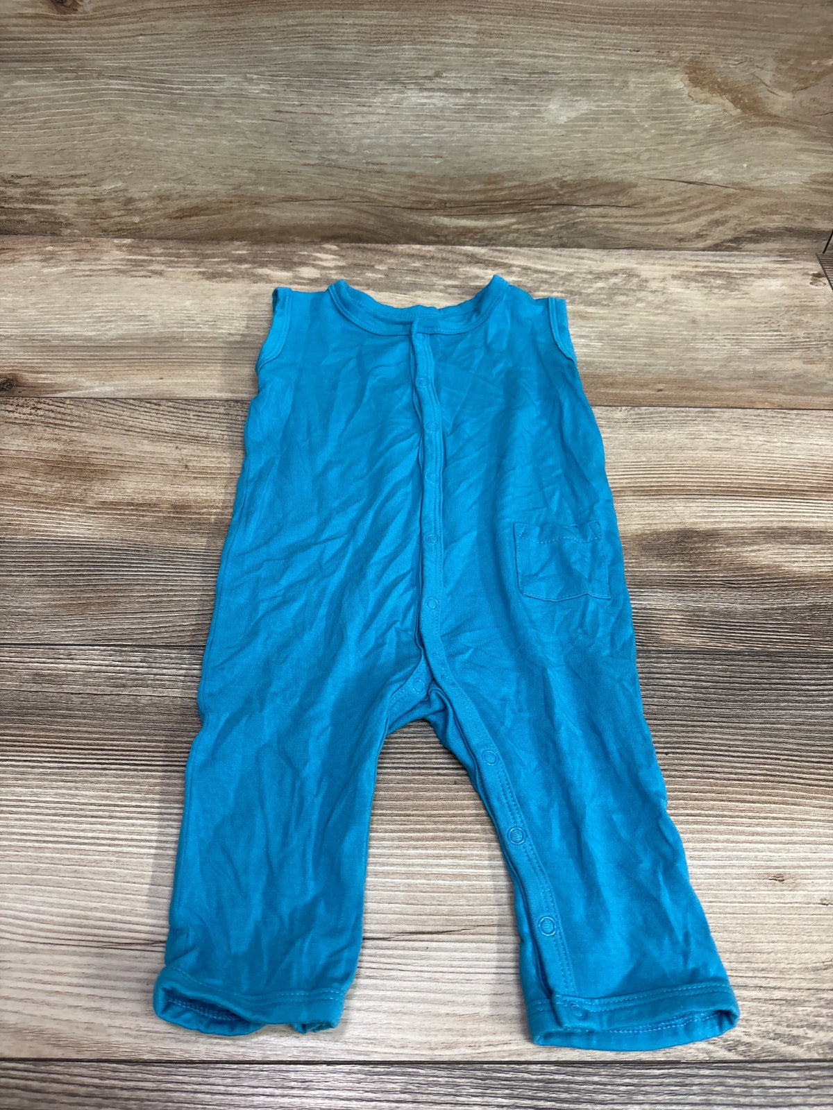 Blue Kyte Baby sleeveless snap jumpsuit for infants laid flat on a wood background