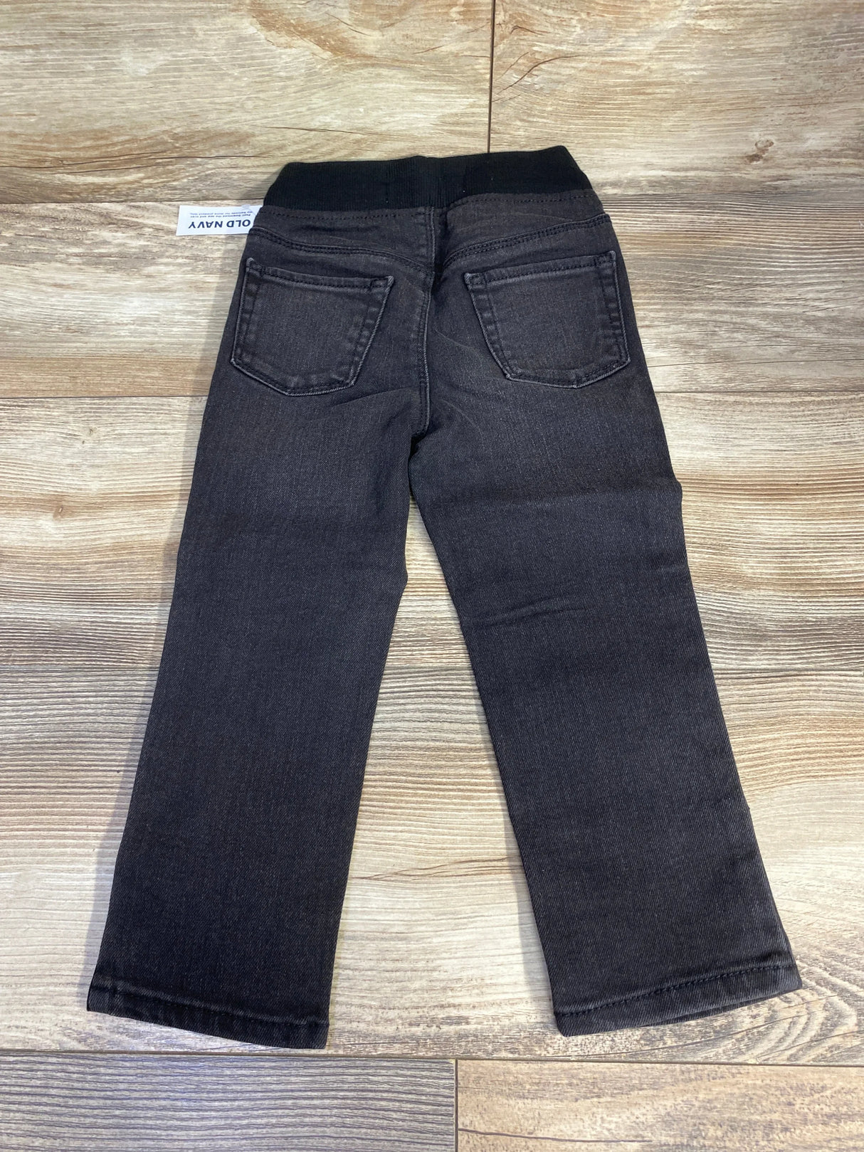 Black toddler jeans with elastic waistband and back pockets on wood background