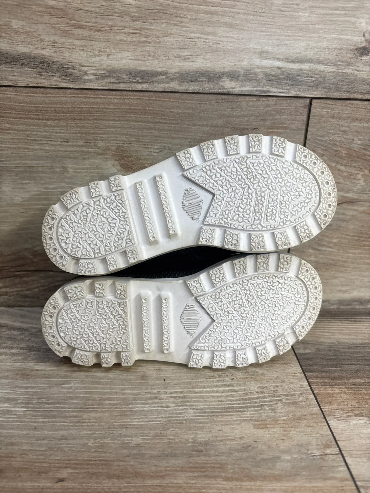 Clean white rubber soles of toddler shoes on wood floor background
