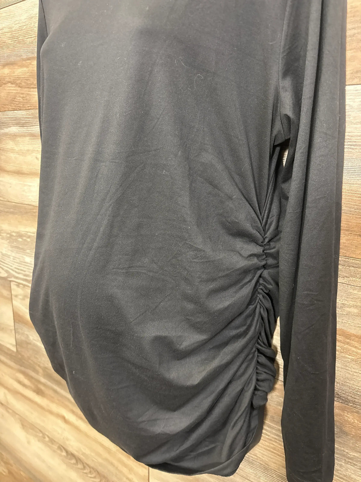 Close-up of Ekouaer Ruched Long Sleeve Shirt showcasing side ruching and long sleeves on a wood background