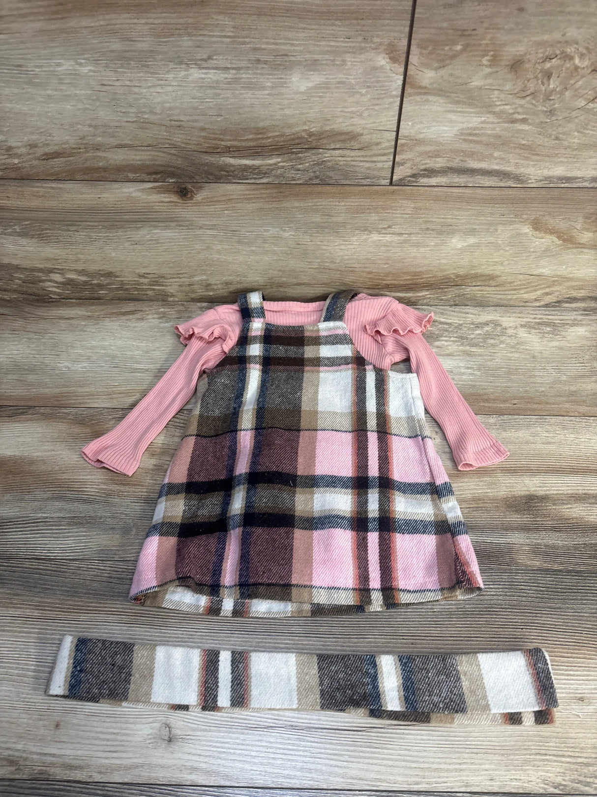 Plaid toddler dress with pink long sleeve shirt and matching sash on wood floor
