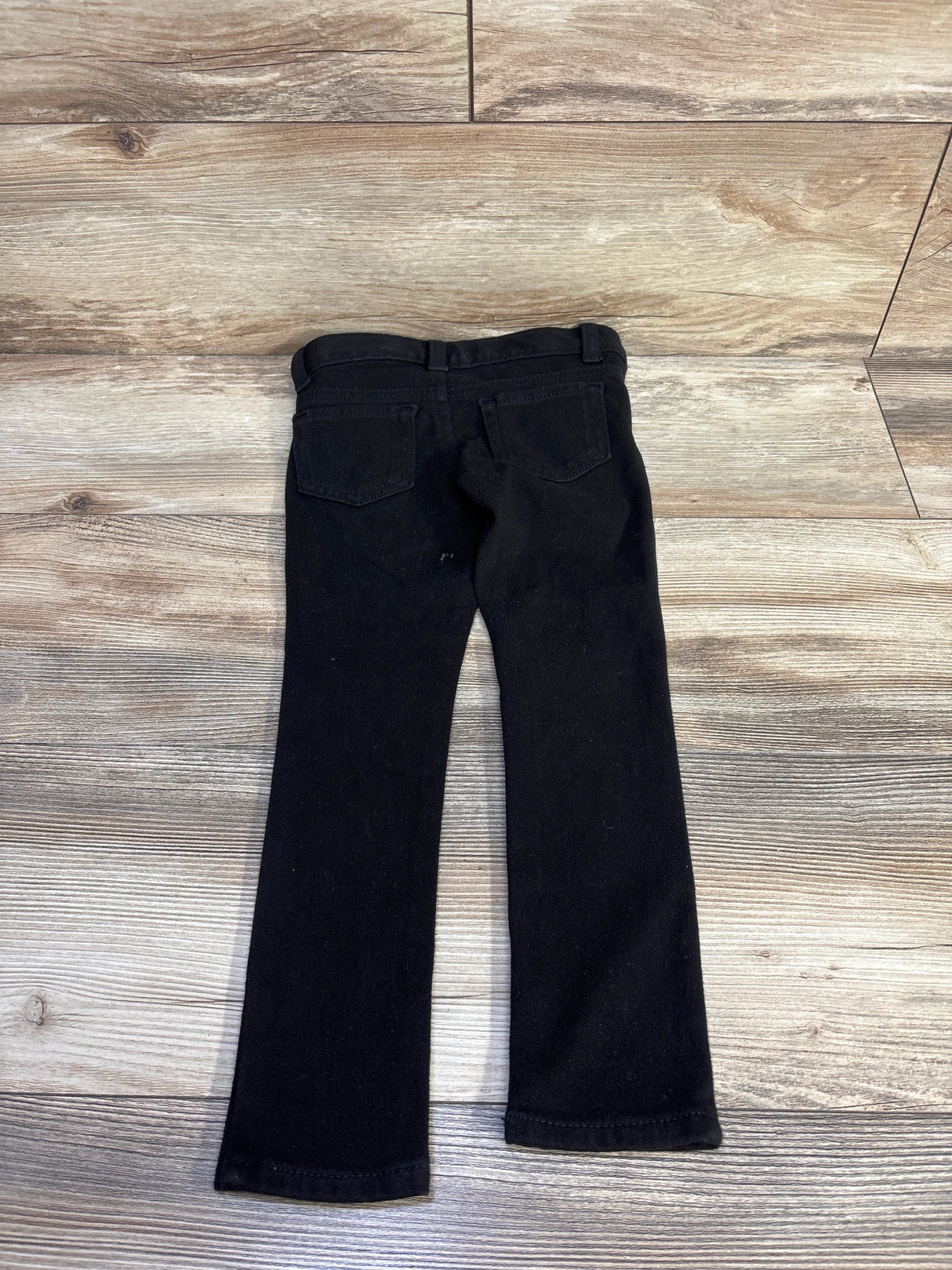 Back view of black Cat & Jack toddler jeggings size 4T showing rear pockets, belt loops, and straight legs on wood floor