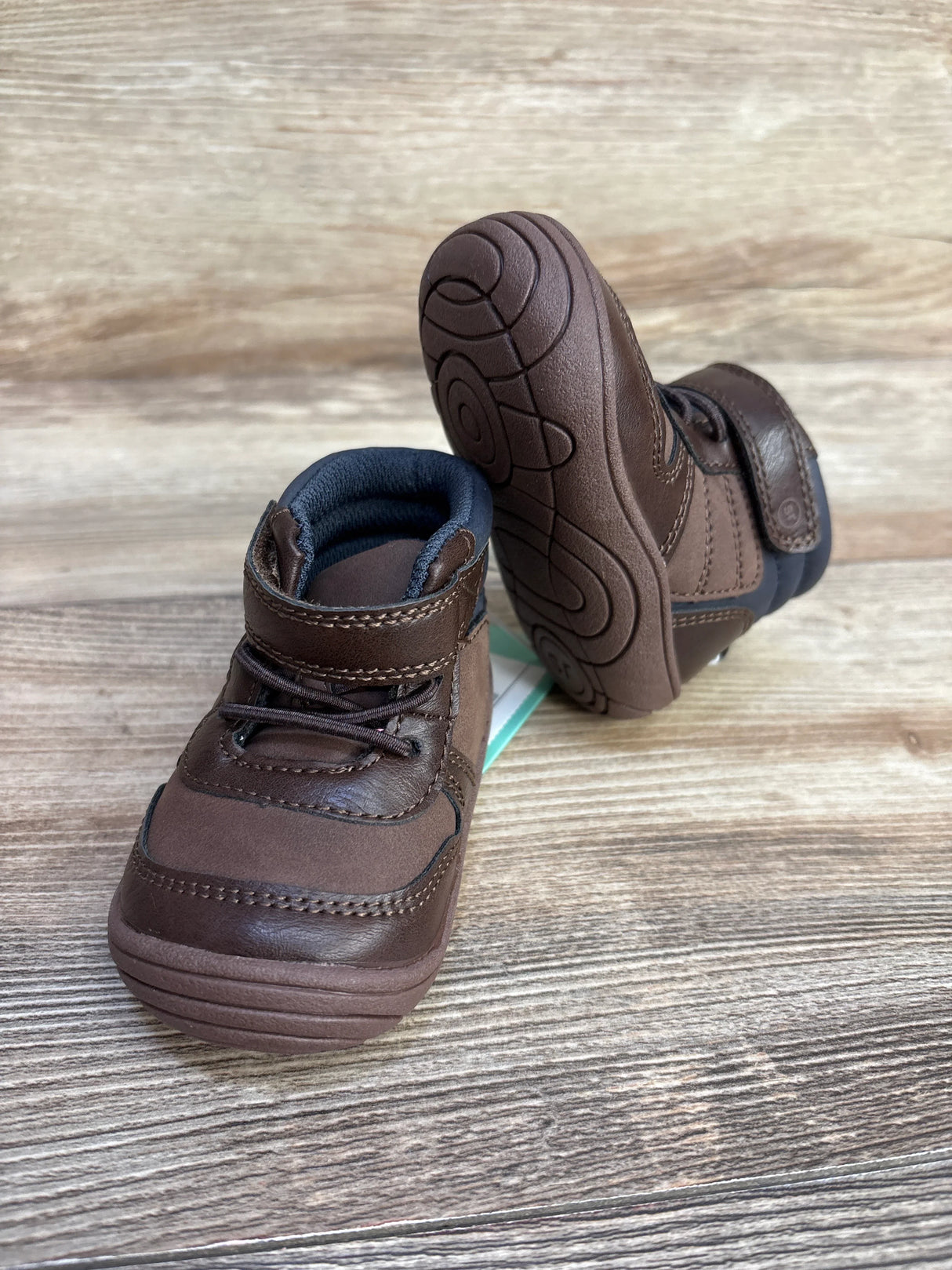 Brown toddler shoes with velcro straps and soft soles on wooden surface