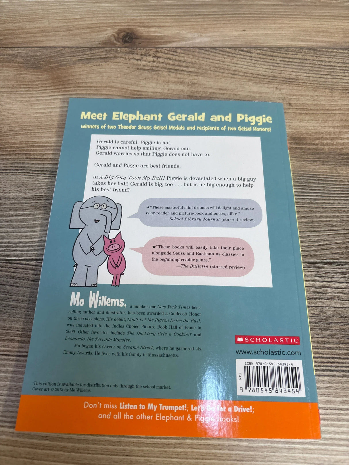 Back cover of a children's book featuring cartoon elephant and pig, text description, and Scholastic logo on a wooden surface.