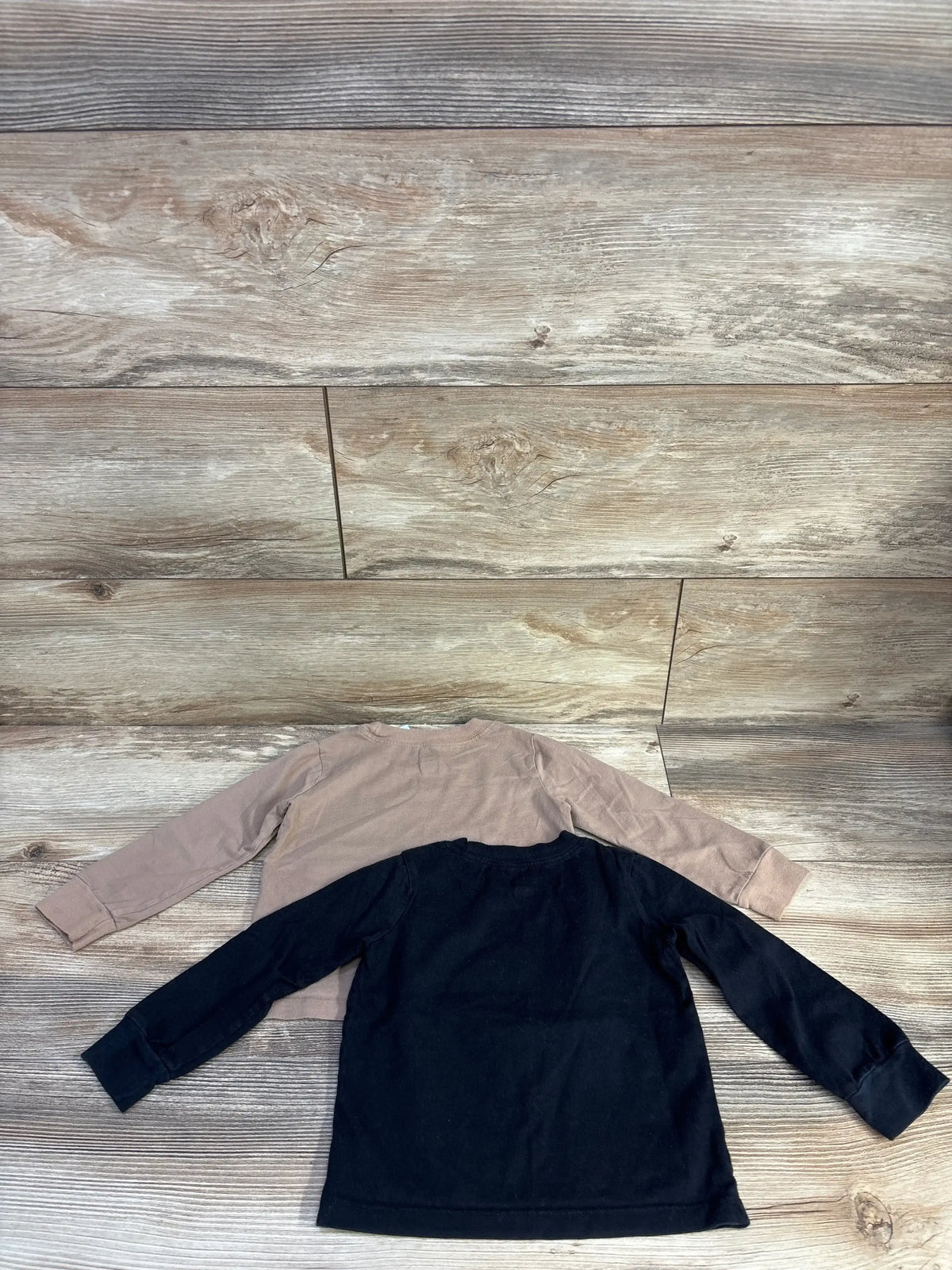 Back view of two Little Star Organic long-sleeve toddler shirts showcasing ribbed cuffs on light wood background