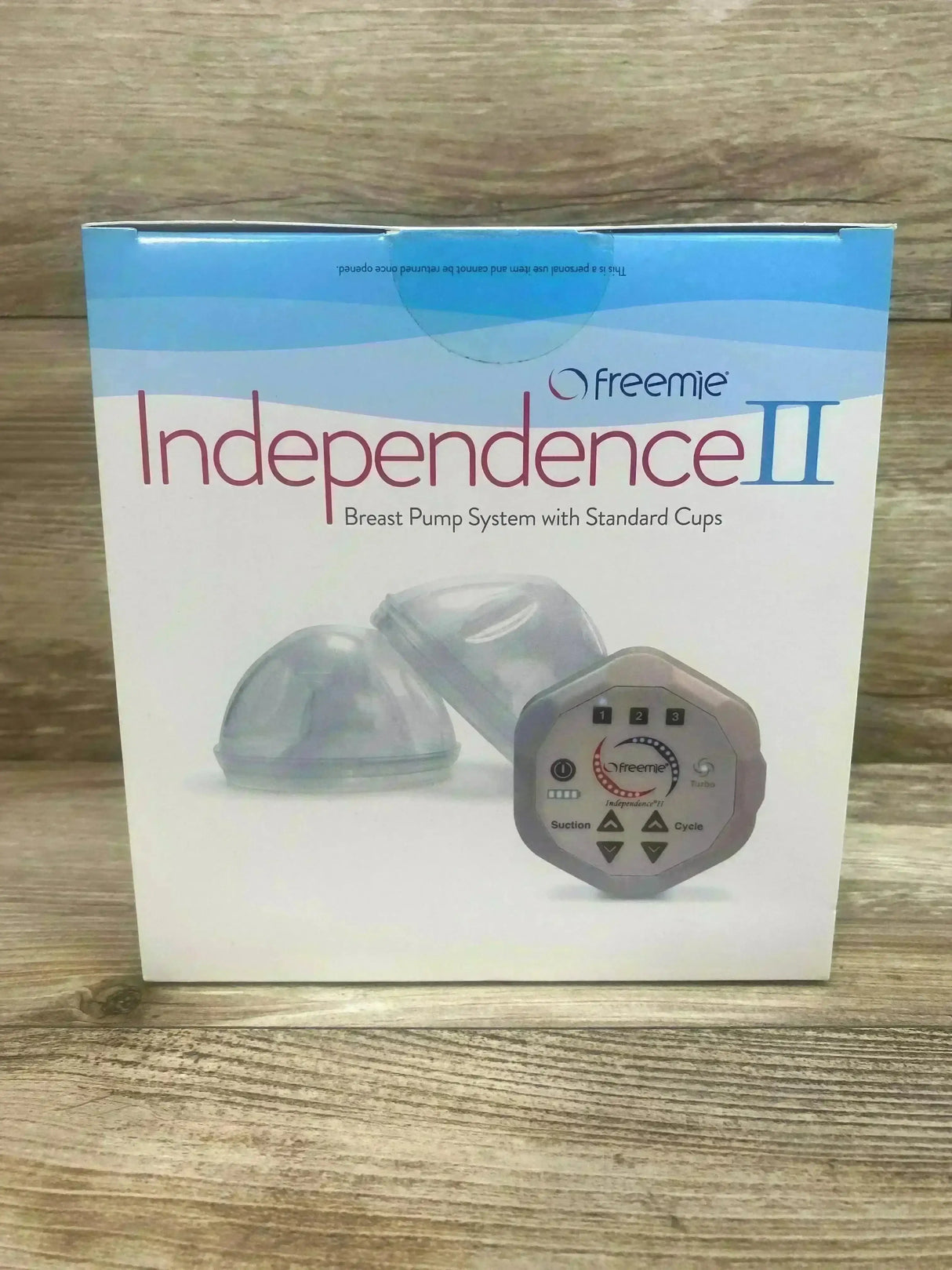Front view of Freemie Independence II standard breast pump box showing two clear cups and control unit on wood background