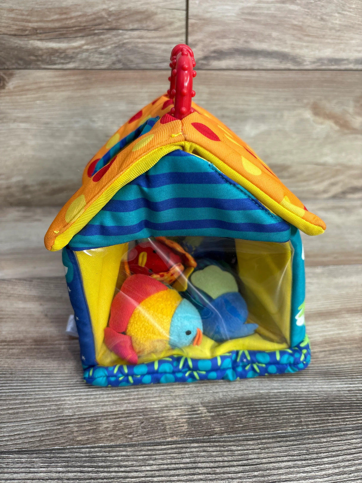 Colorful plush birdhouse toy with fabric birds, striped and polka dot roof, wood background