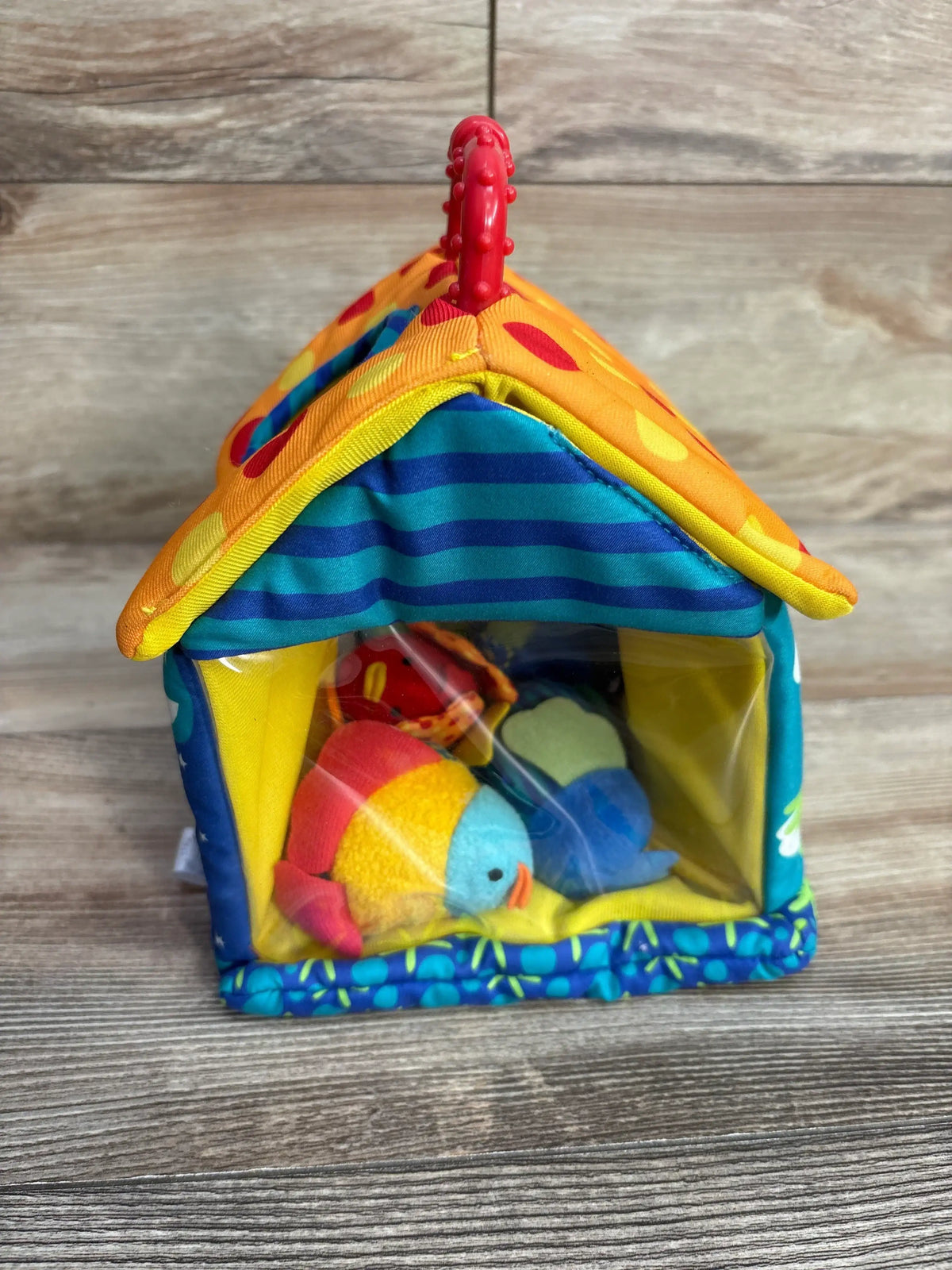 Colorful plush birdhouse toy with fabric birds, striped and polka dot roof, wood background