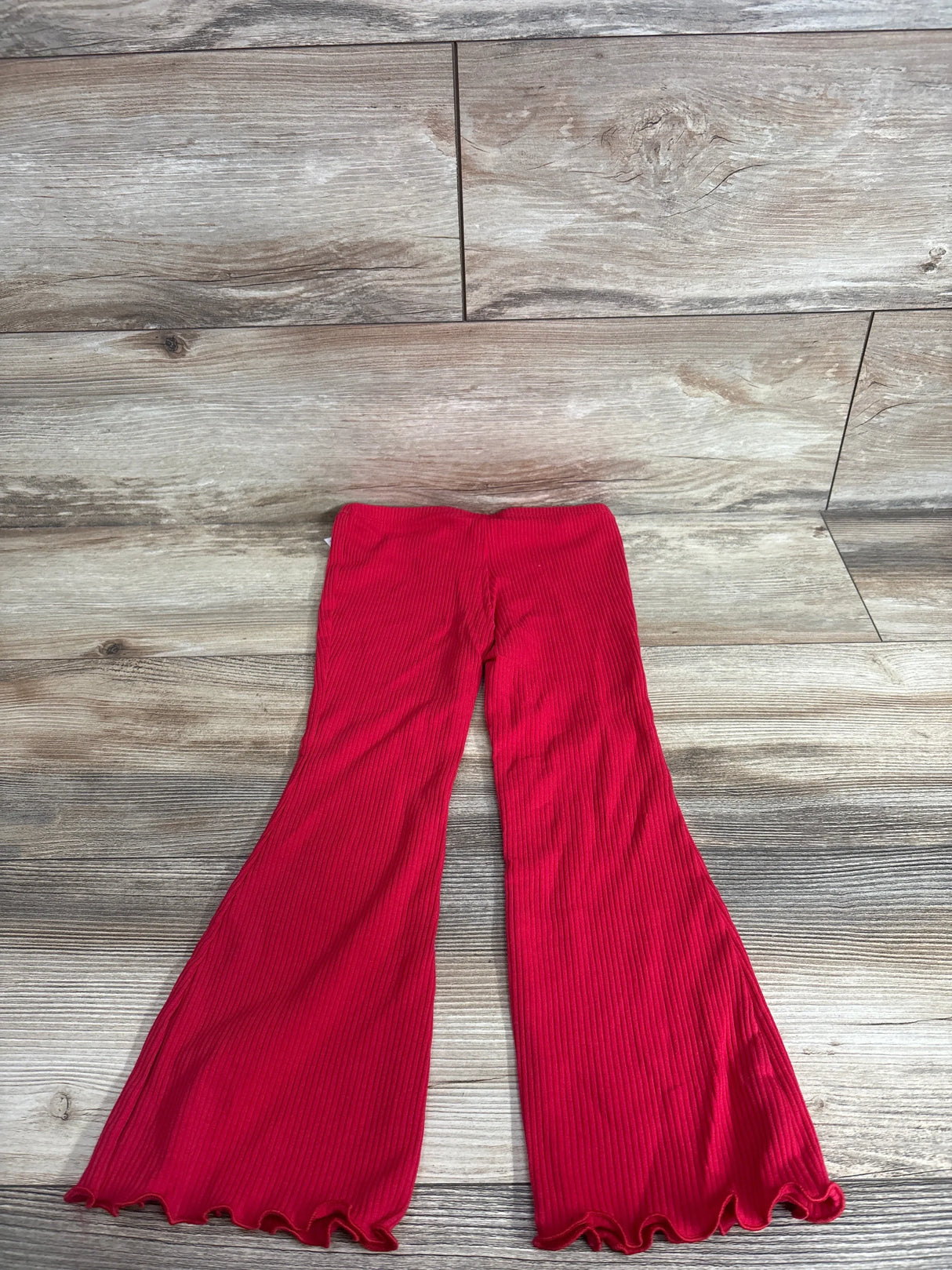Flat lay of Old Navy girls’ ribbed red flare leggings, size 4T, showing ribbed texture and lettuce hem on wood background
