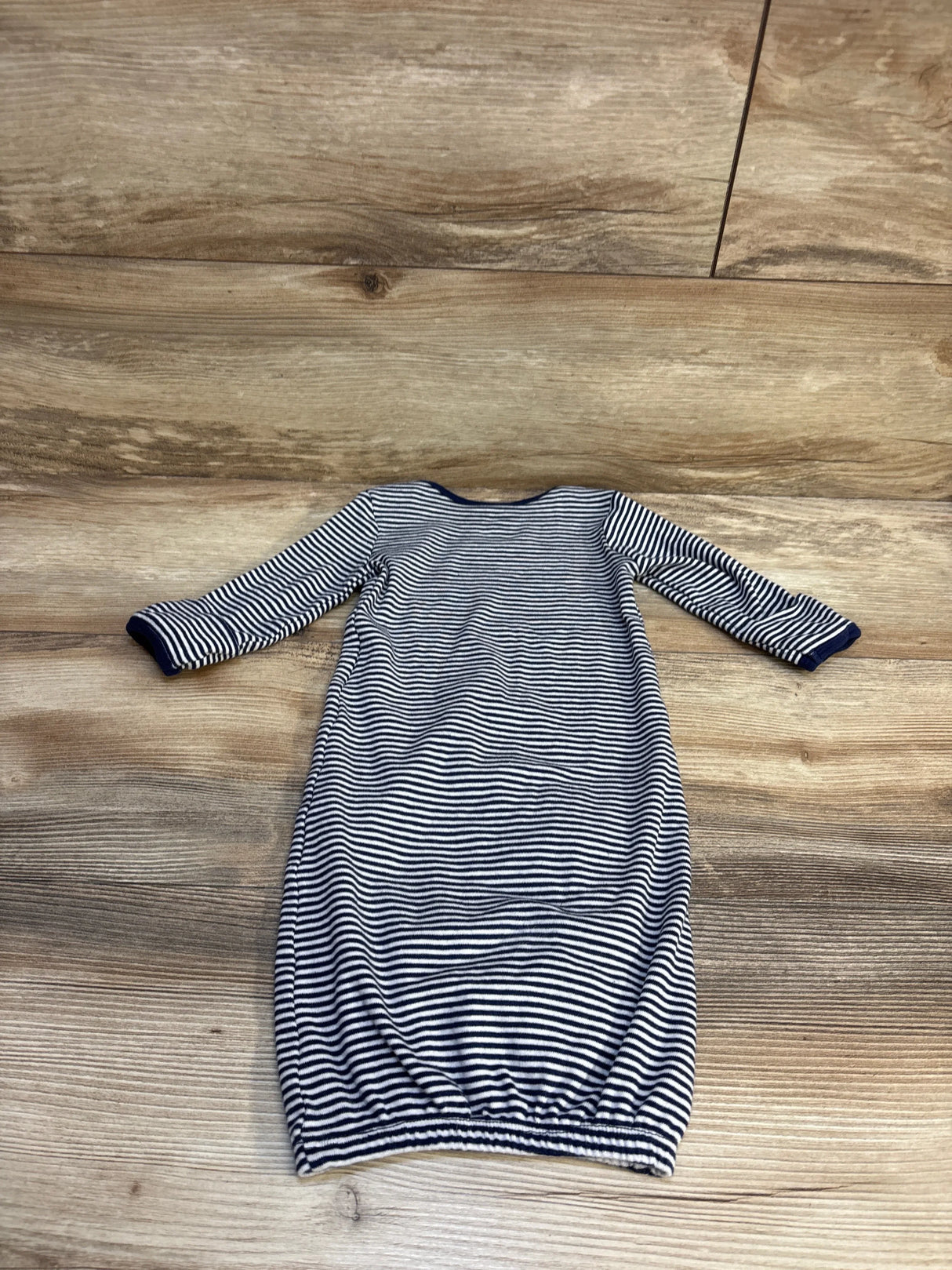 Striped newborn baby gown with navy and white long sleeves on wood background