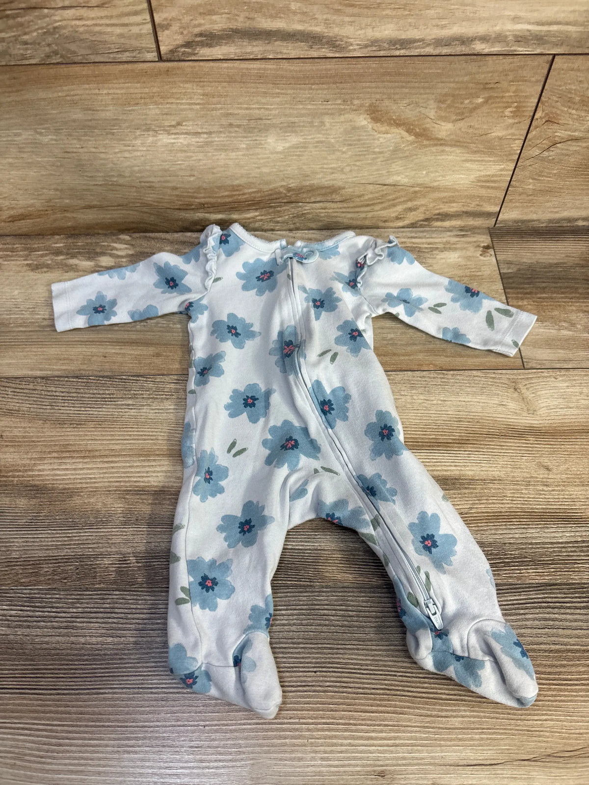 Front view of Just One You blue floral sleeper, size 3 months, showcasing footed legs and front zipper on a wood floor