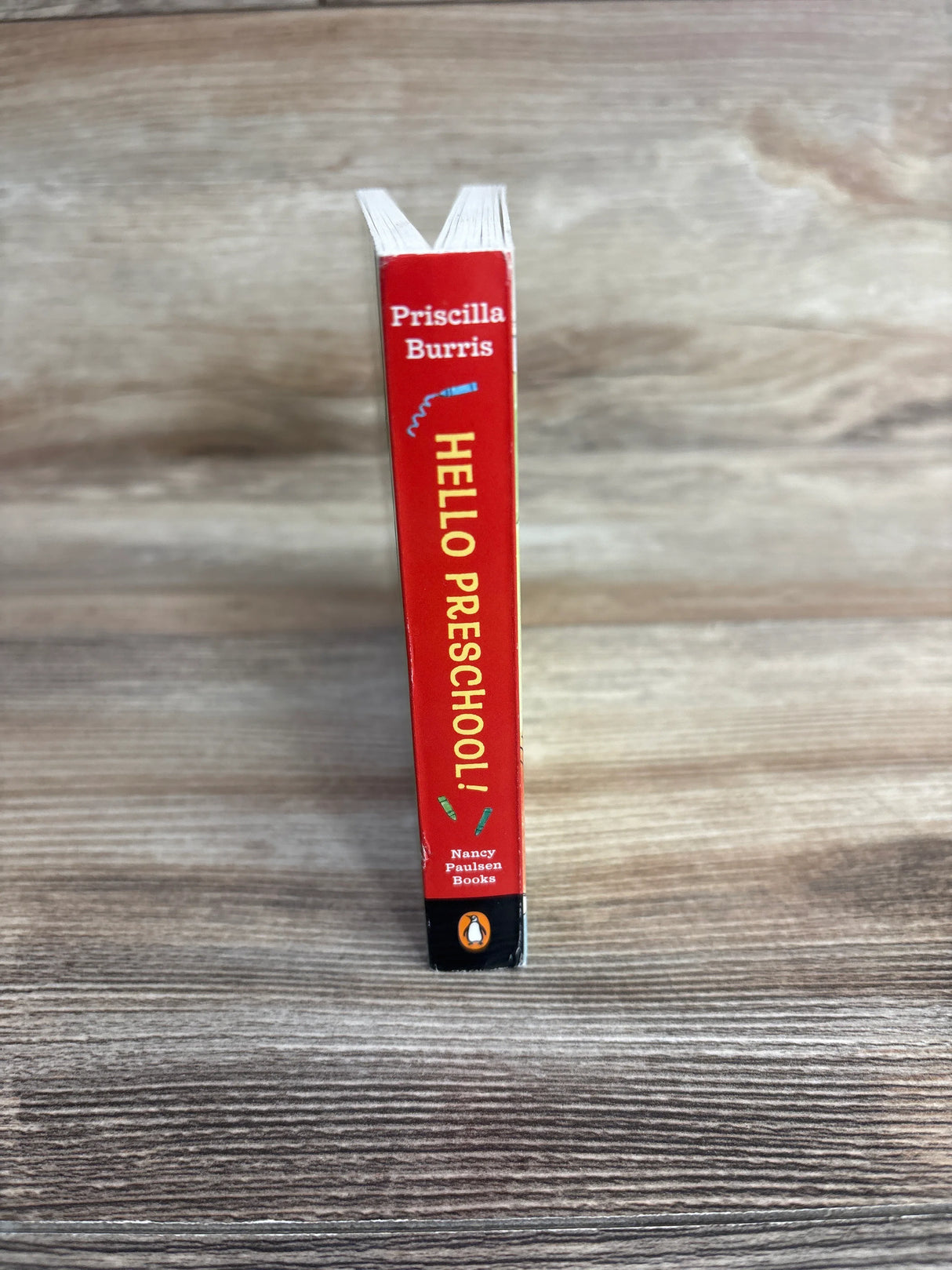 Spine of the children's book 'Hello Preschool!' by Priscilla Burris on wooden surface