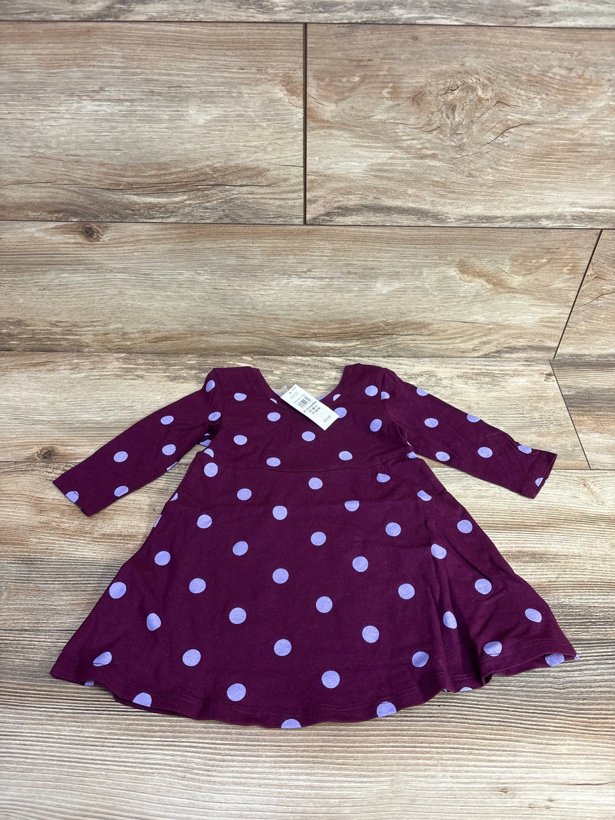 Purple long sleeve toddler dress with light blue polka dots on wood background