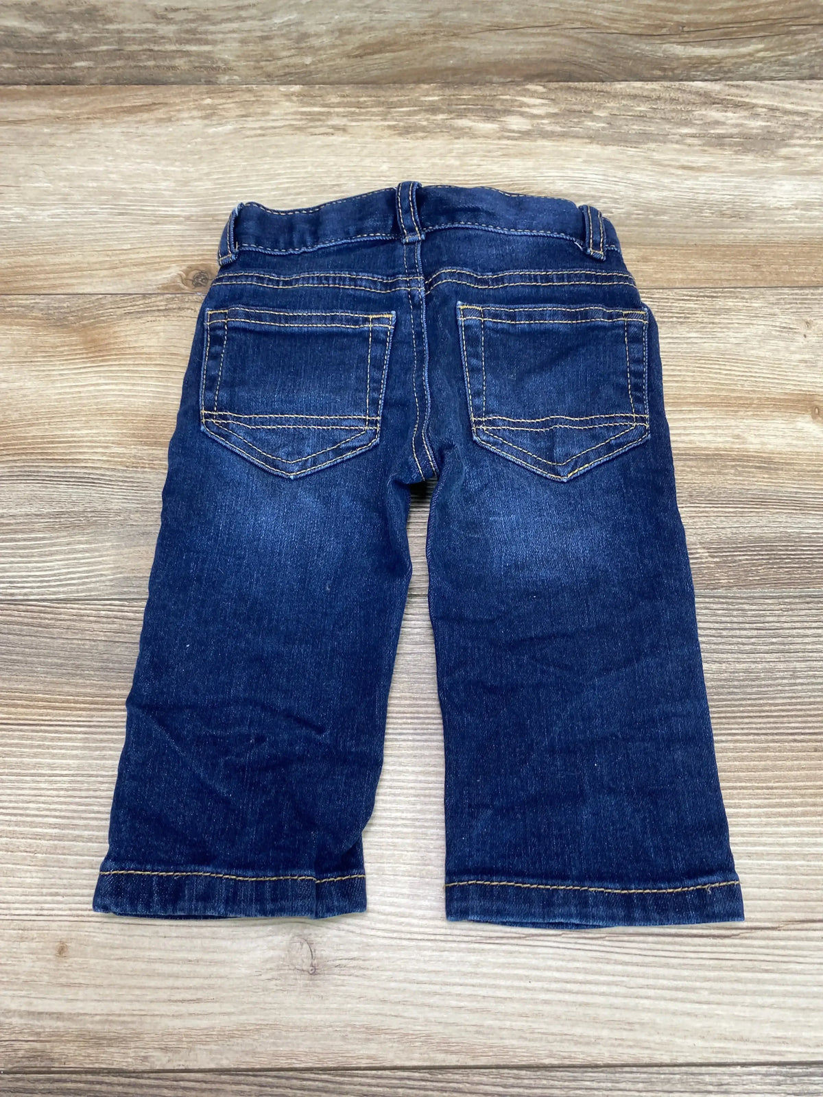 Back view of Cat and Jack straight jeans size 12 months showing back pockets and elastic waist on light wood background