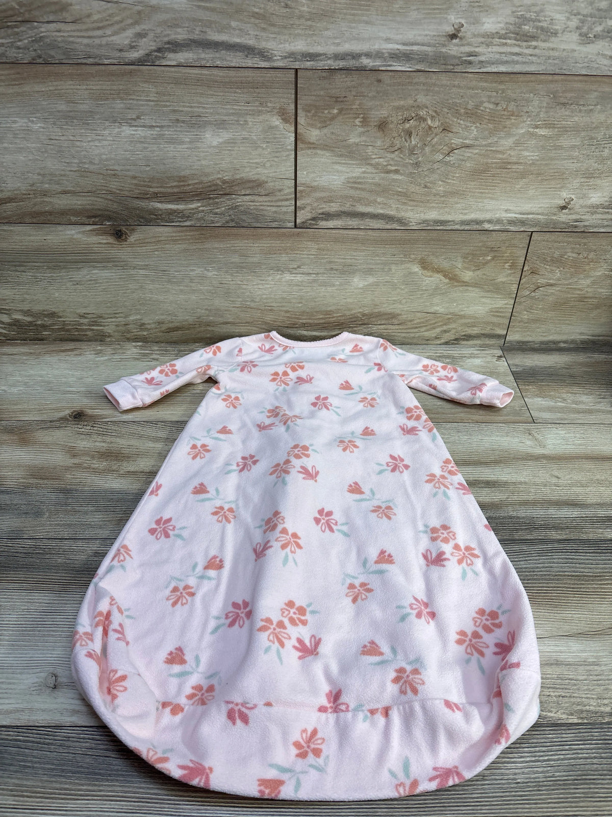 Front view of Just One You pink blanket sleep sack for 3 to 6 months, with floral print and long sleeves on a wood floor