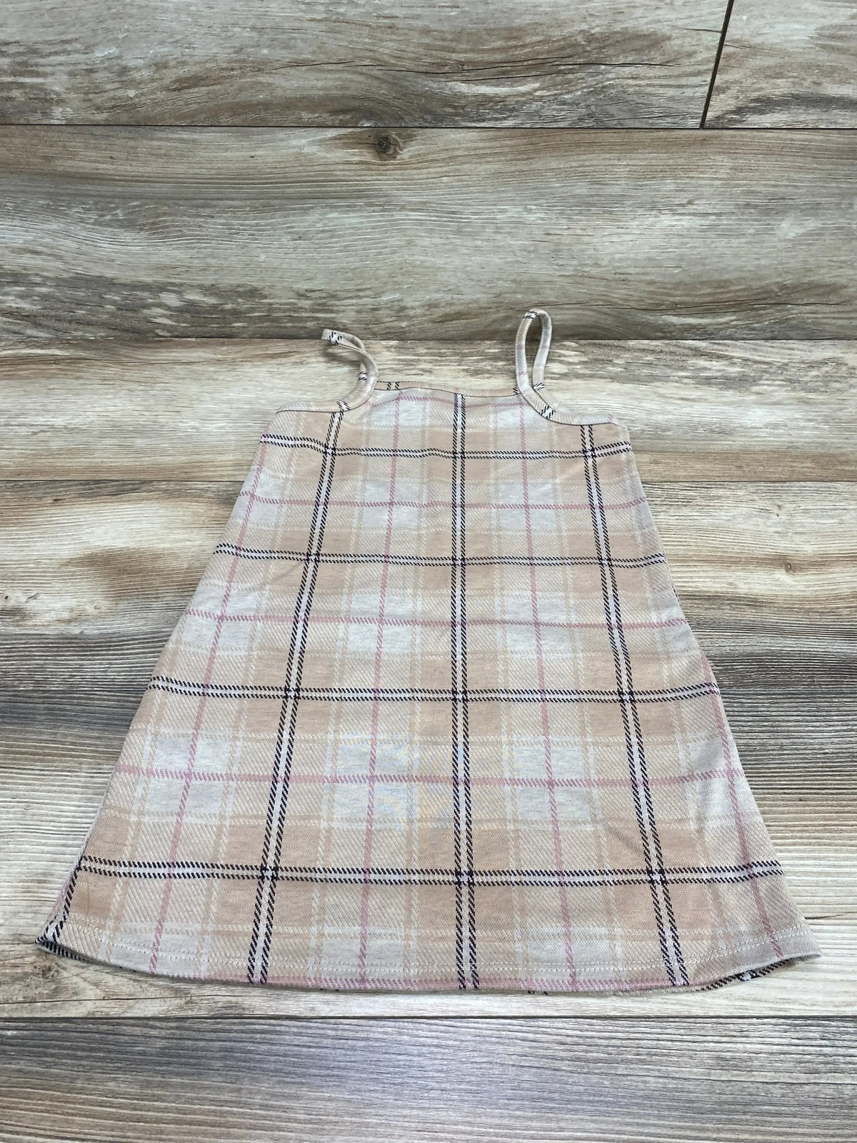 Flat lay of Btween plaid dress 4T, brown with pink and black checks, showing thin straps and A-line shape on wood floor