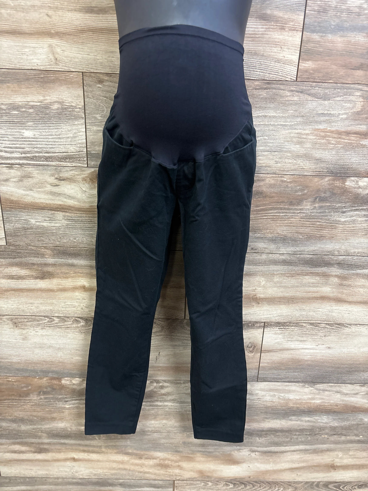 Front view of Old Navy maternity Pixie full-panel black pants showcasing full belly panel and slim ankle-length legs on wood floor background