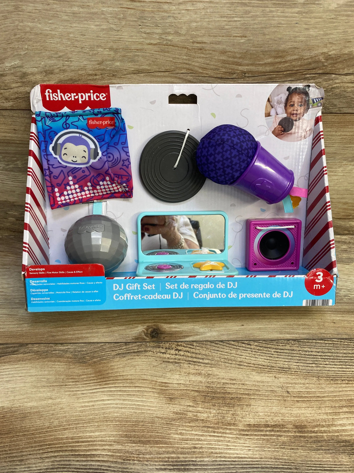 Front view of Fisher-Price DJ gift set showing purple microphone, toy turntable, mirror, and speaker on wood background