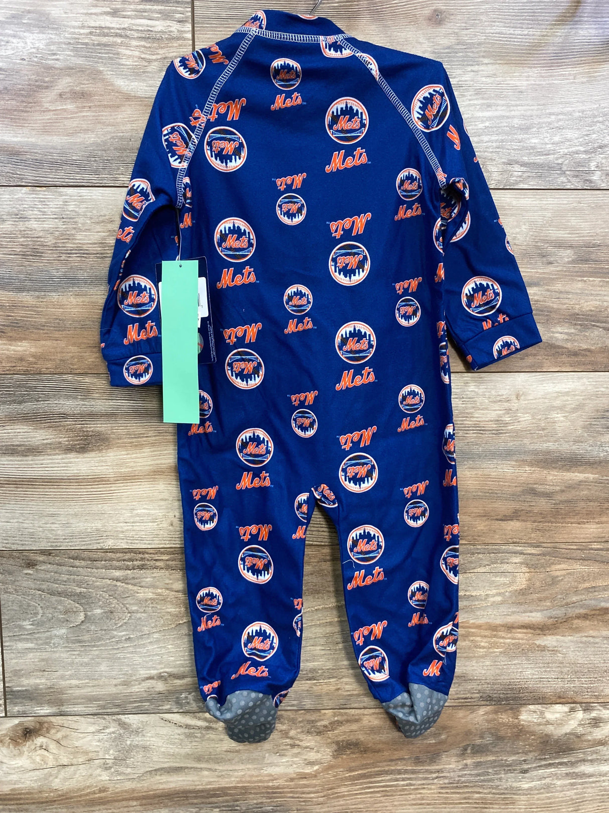 Back view of New York Mets raglan zip-up 18m footie showing all-over Mets print, gray grip soles on wood background