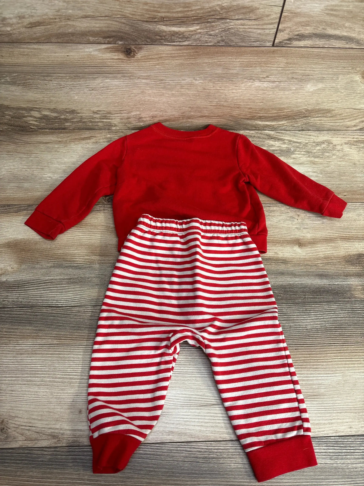 Red long sleeve top and red white striped pants baby outfit on wood floor