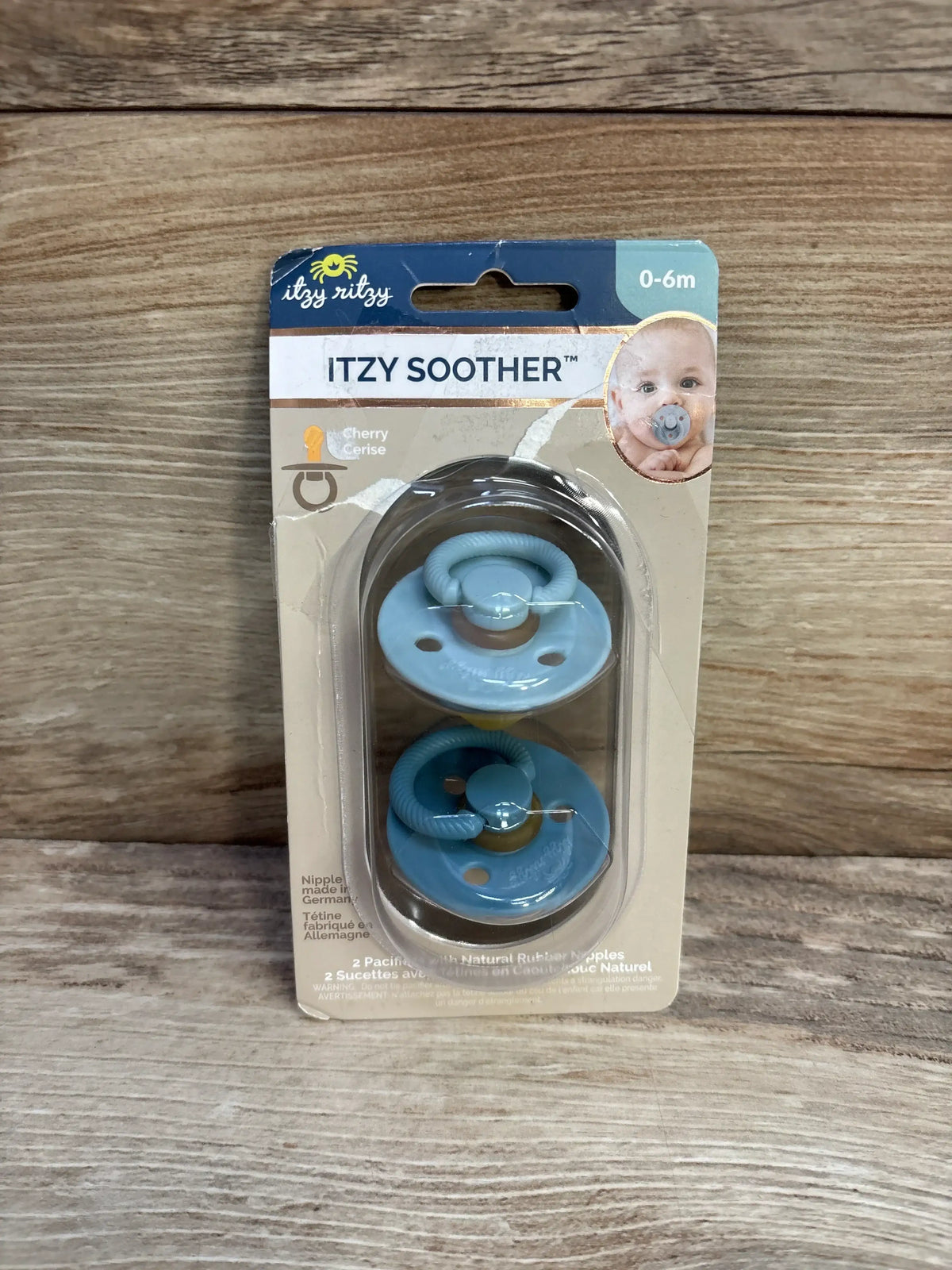 Front view of Itzy Ritzy natural rubber soothers (0-6m), two blue pacifiers in blister pack on wood background
