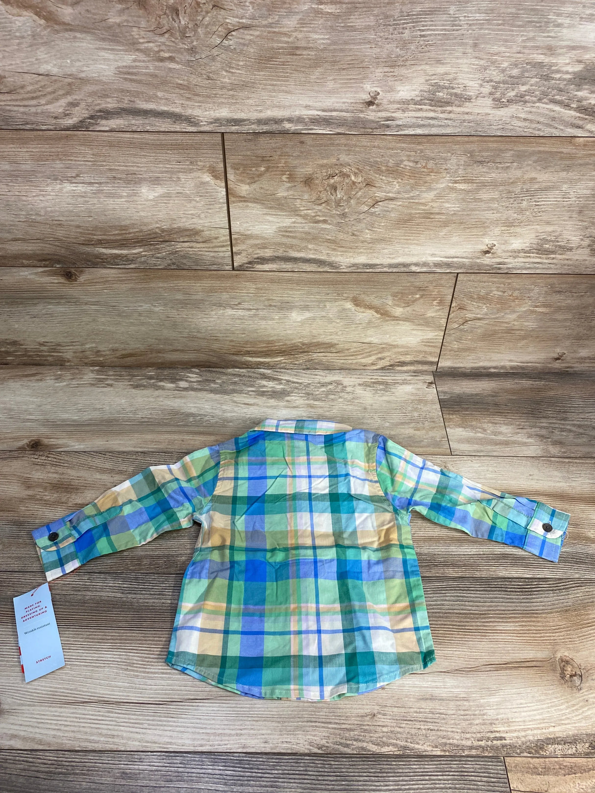 Back view of a colorful plaid long-sleeve children's shirt on wood floor background