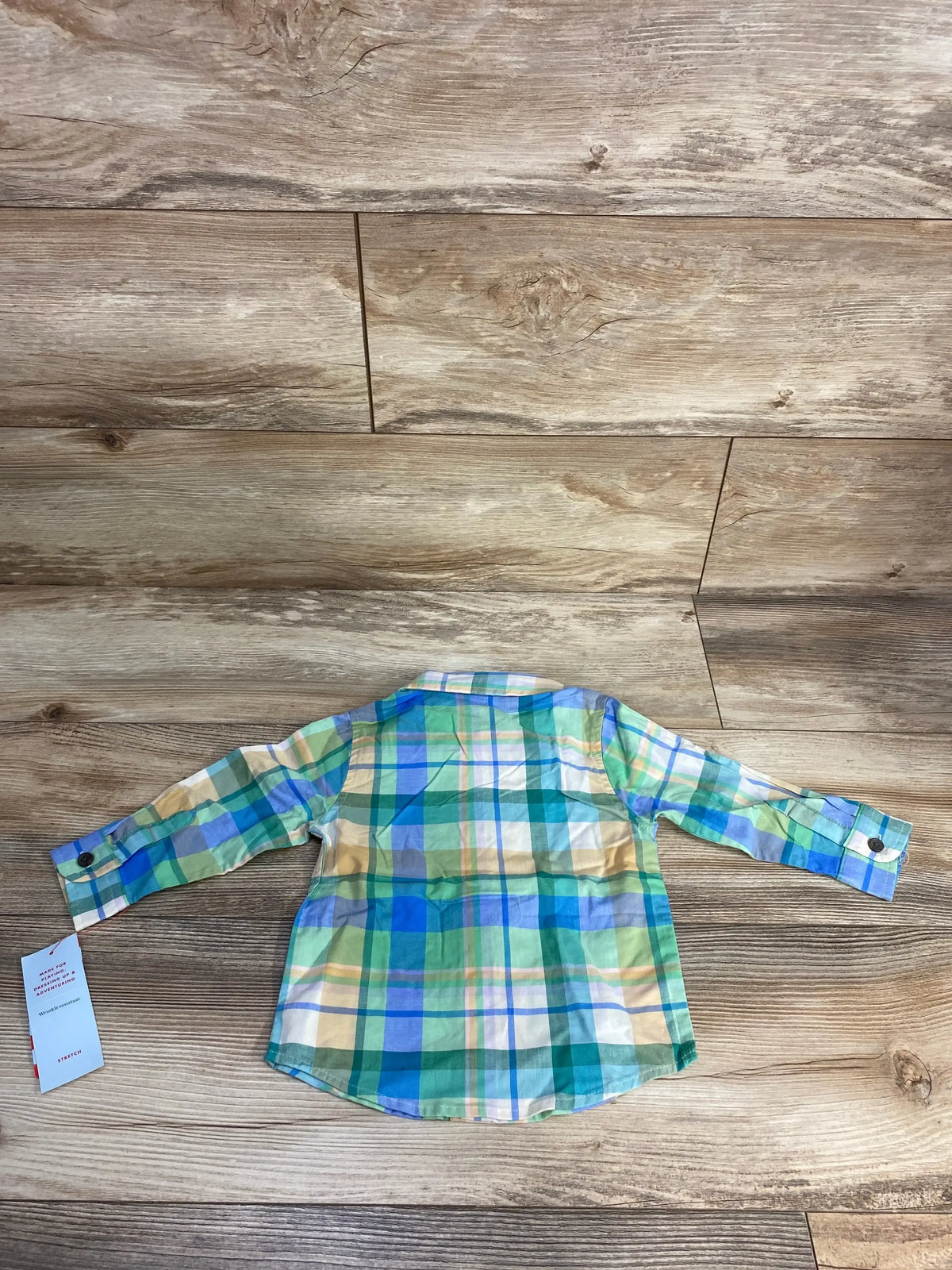 Back view of a colorful plaid long-sleeve children's shirt on wood floor background