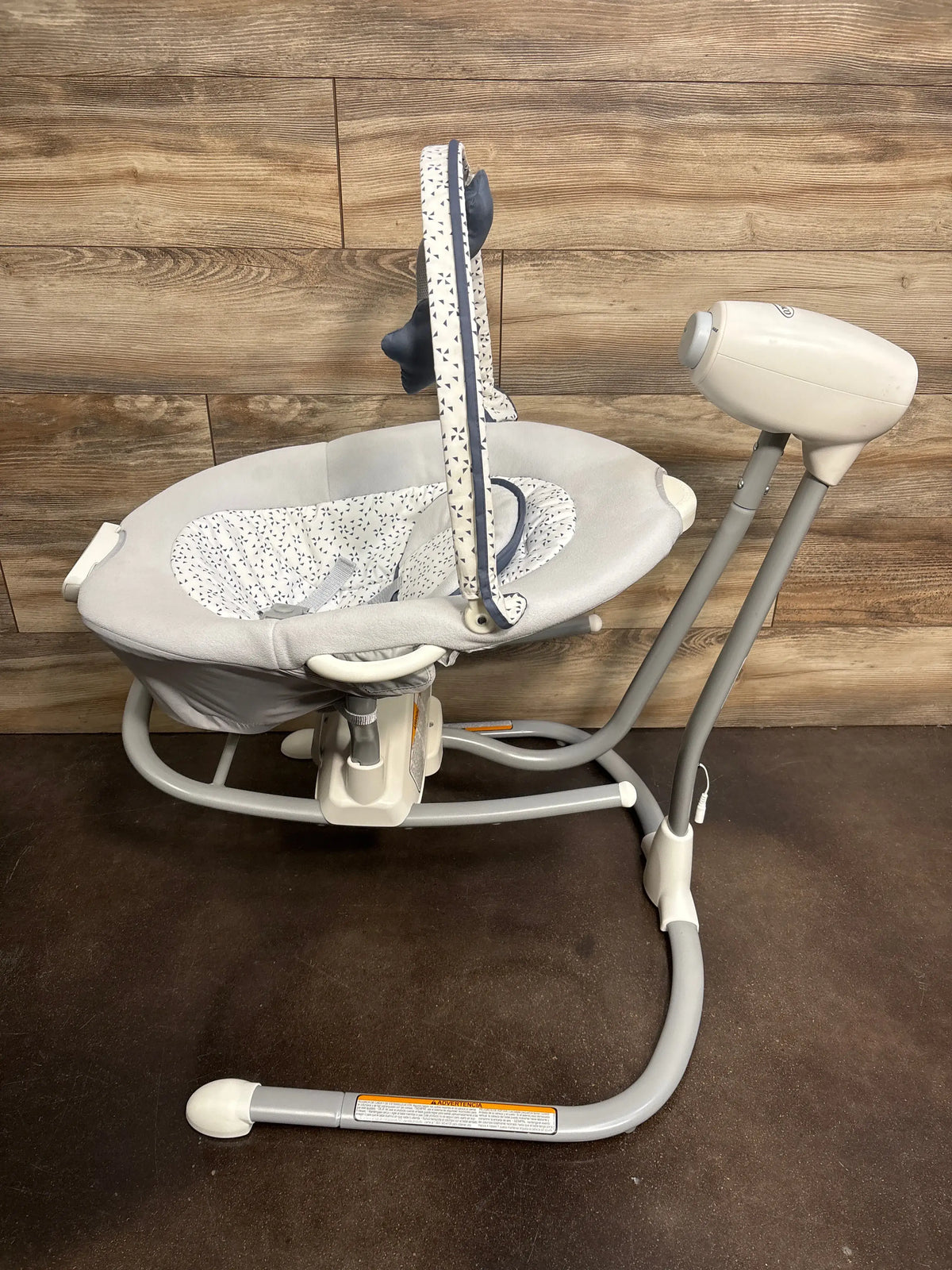 Three-quarter view of Graco Soothe ‘n Sway LX swing and portable rocker with padded seat and toy bar on wood floor