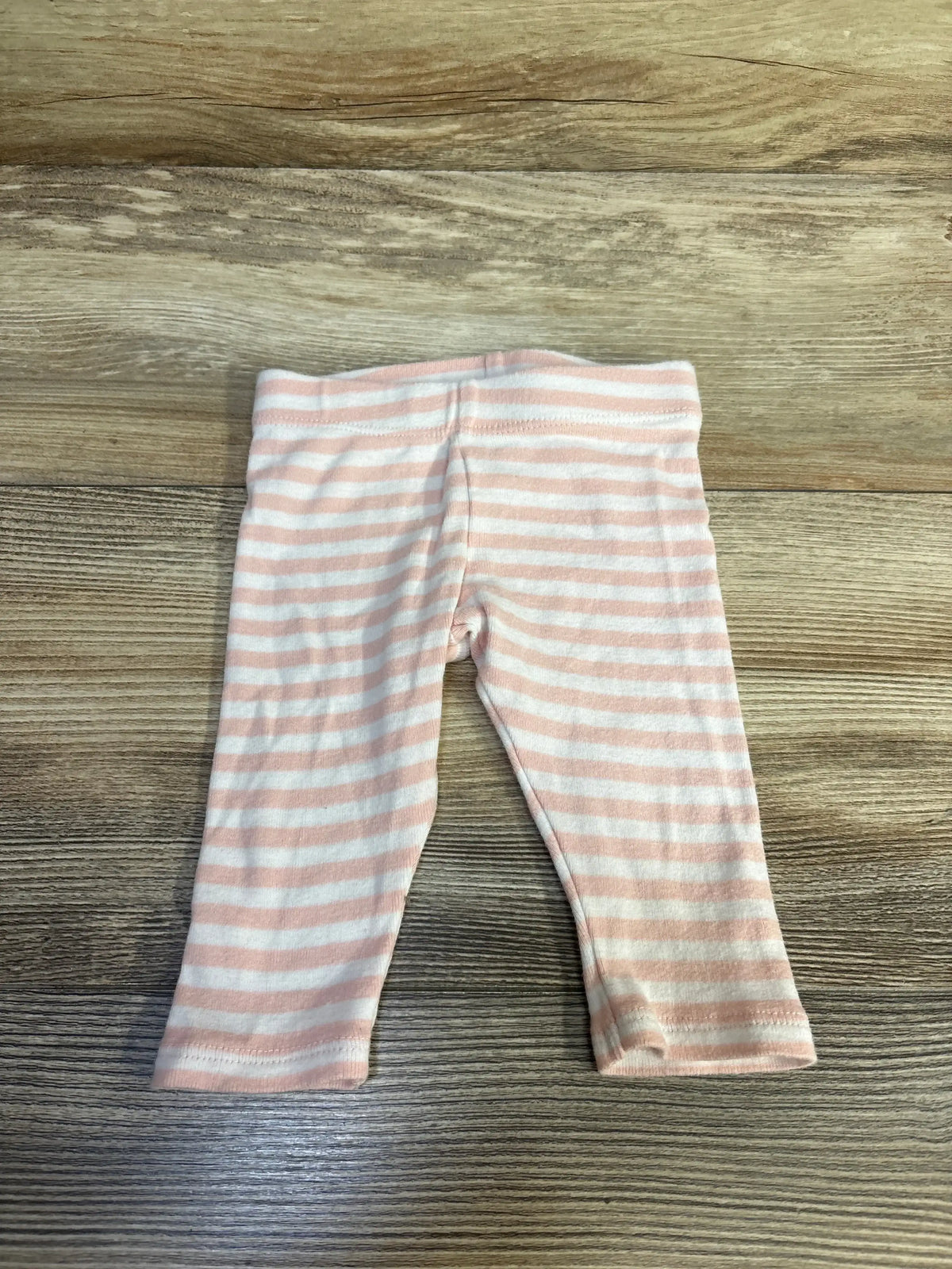 Flat lay of Norstrom baby leggings with pink and white stripes showcasing elastic waistband and full-length legs on wood background