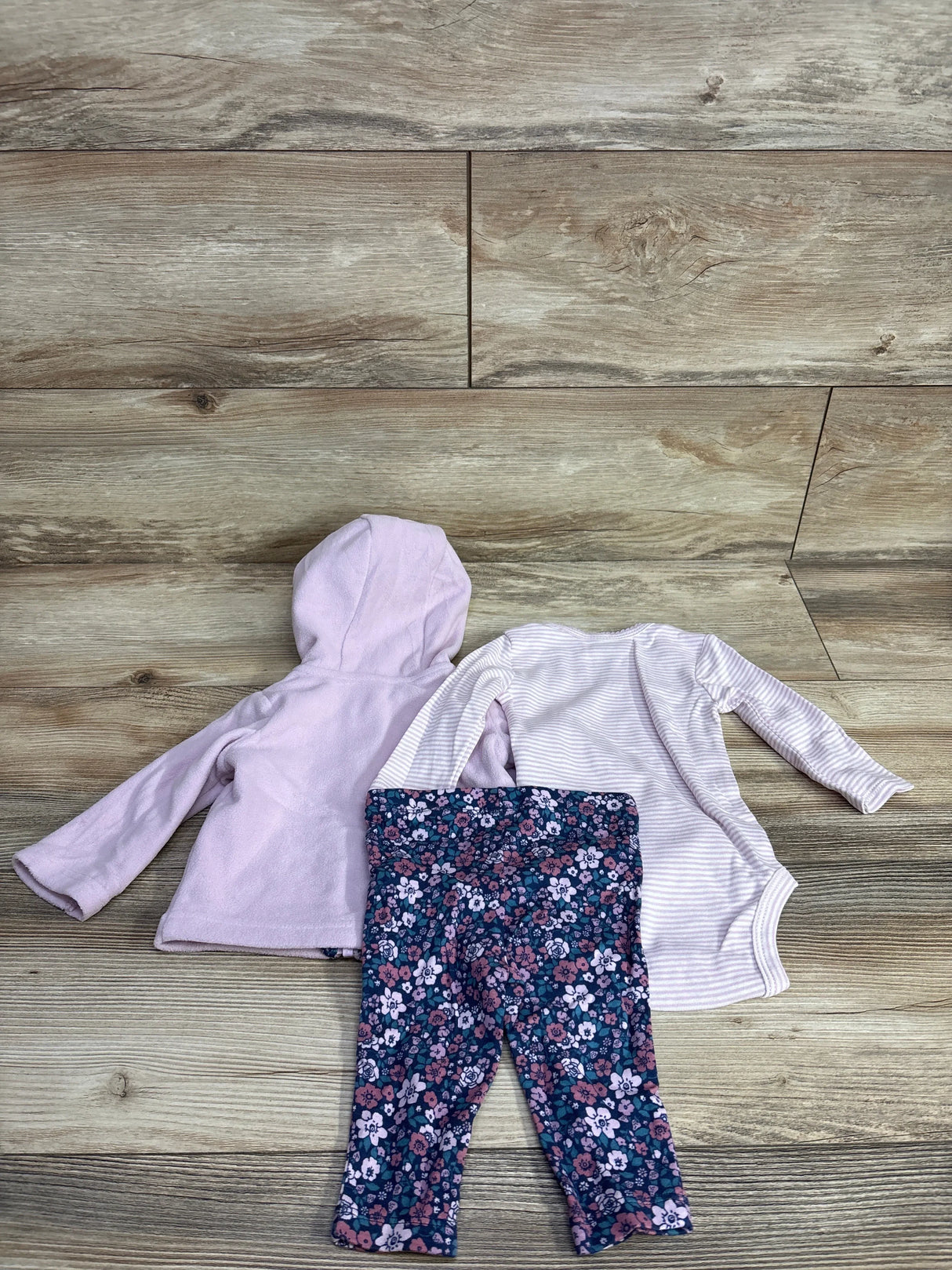 Baby girl outfit with lavender hoodie, striped bodysuit, and floral leggings on wood background