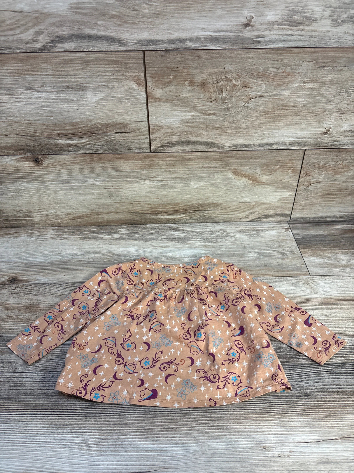 Flat lay of Wrangler Cowboy Hats and Flowers Tan Top size 12m showcasing long sleeve top with cowboy hat and floral print on wood plank surface